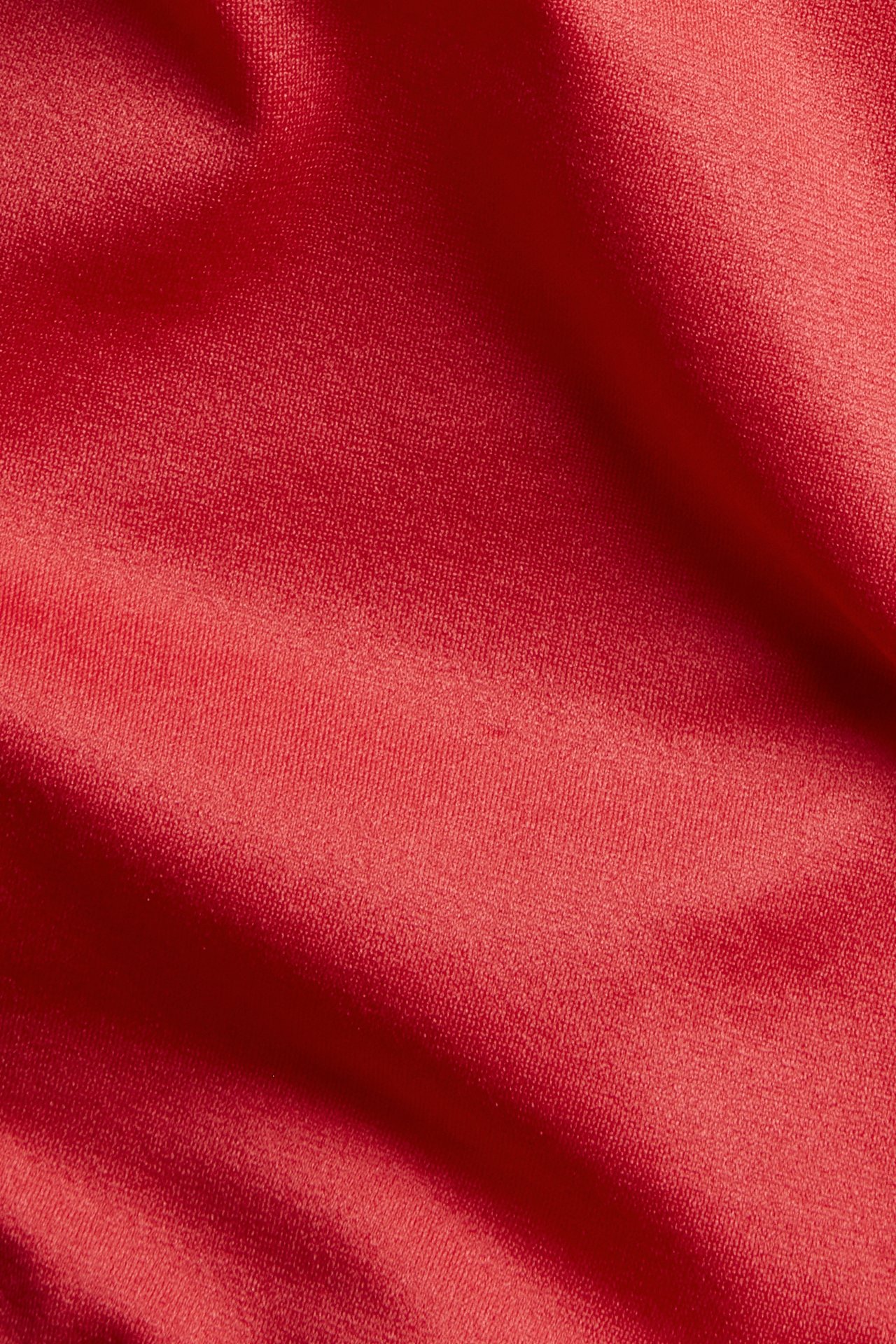 Nærbilde av rødt, glatt, tøyelig polyamid-elastanstoff for en brasiliansk truse.