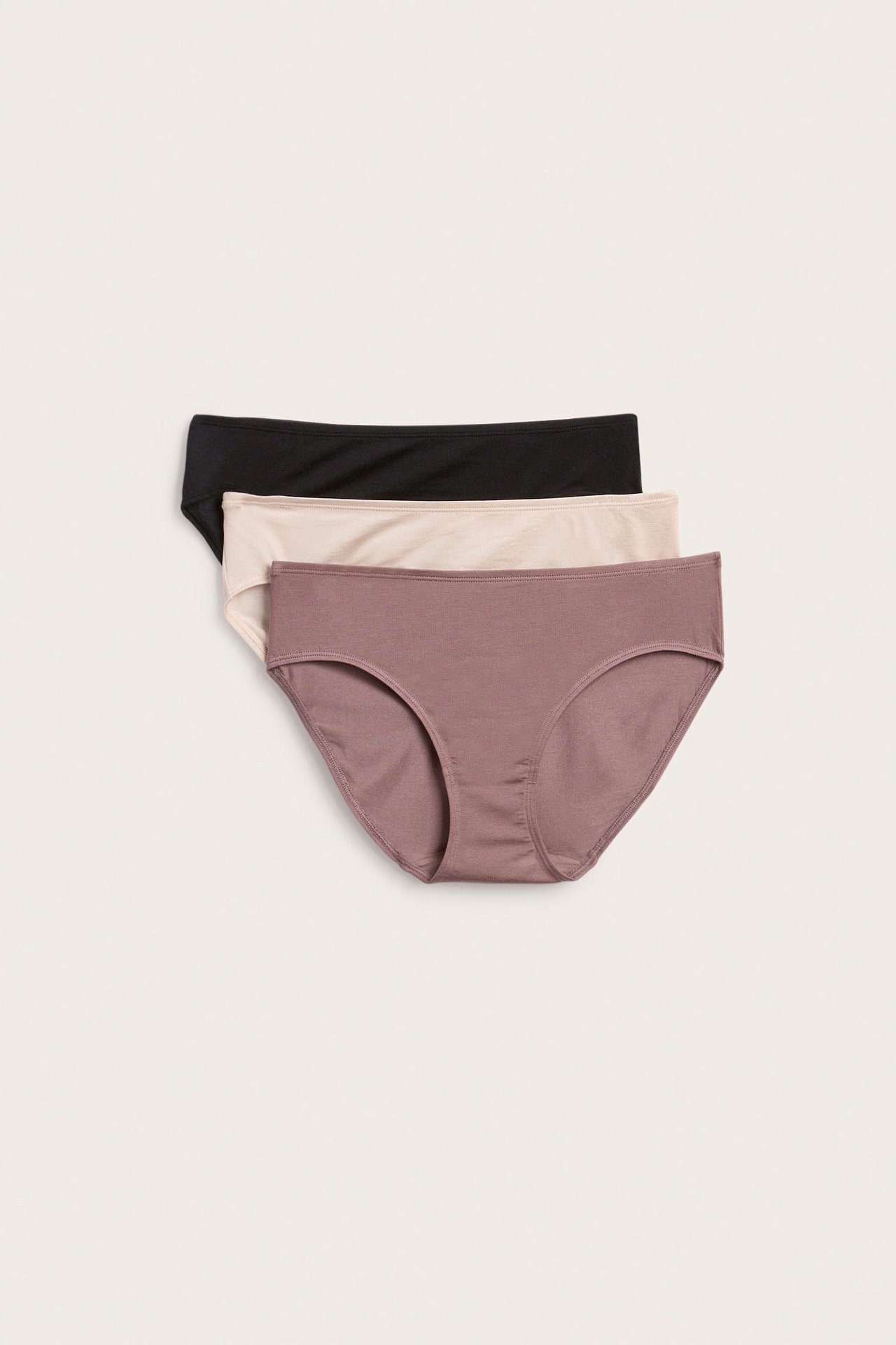Ovenfra-visning av en mørkrosa lyocell-brief, stablet med en beige og en svart lyocell-brief.