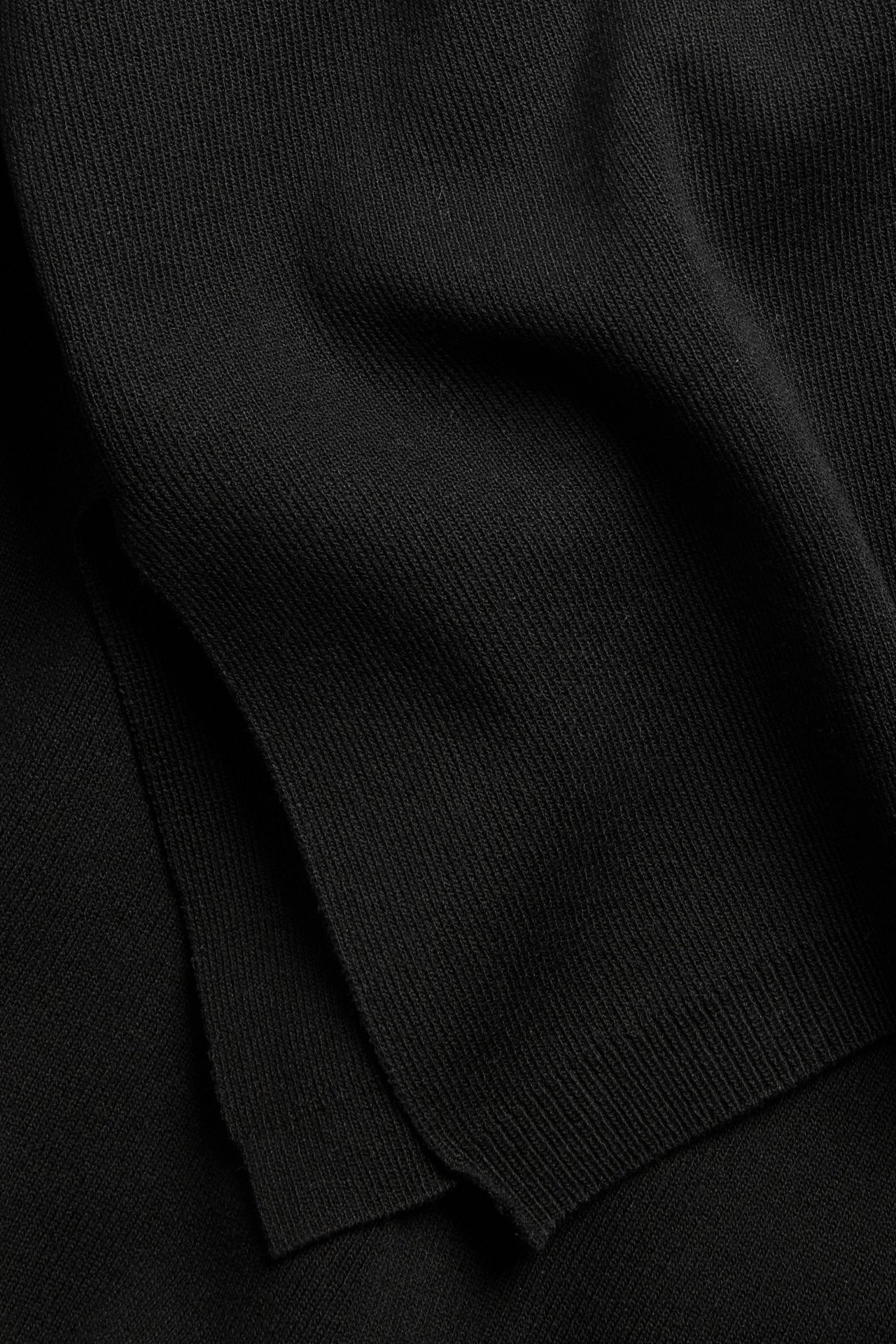 Lähikuva mustasta, hienoneulotusta neulekankaasta, joka esittelee sen sileää neuletta.