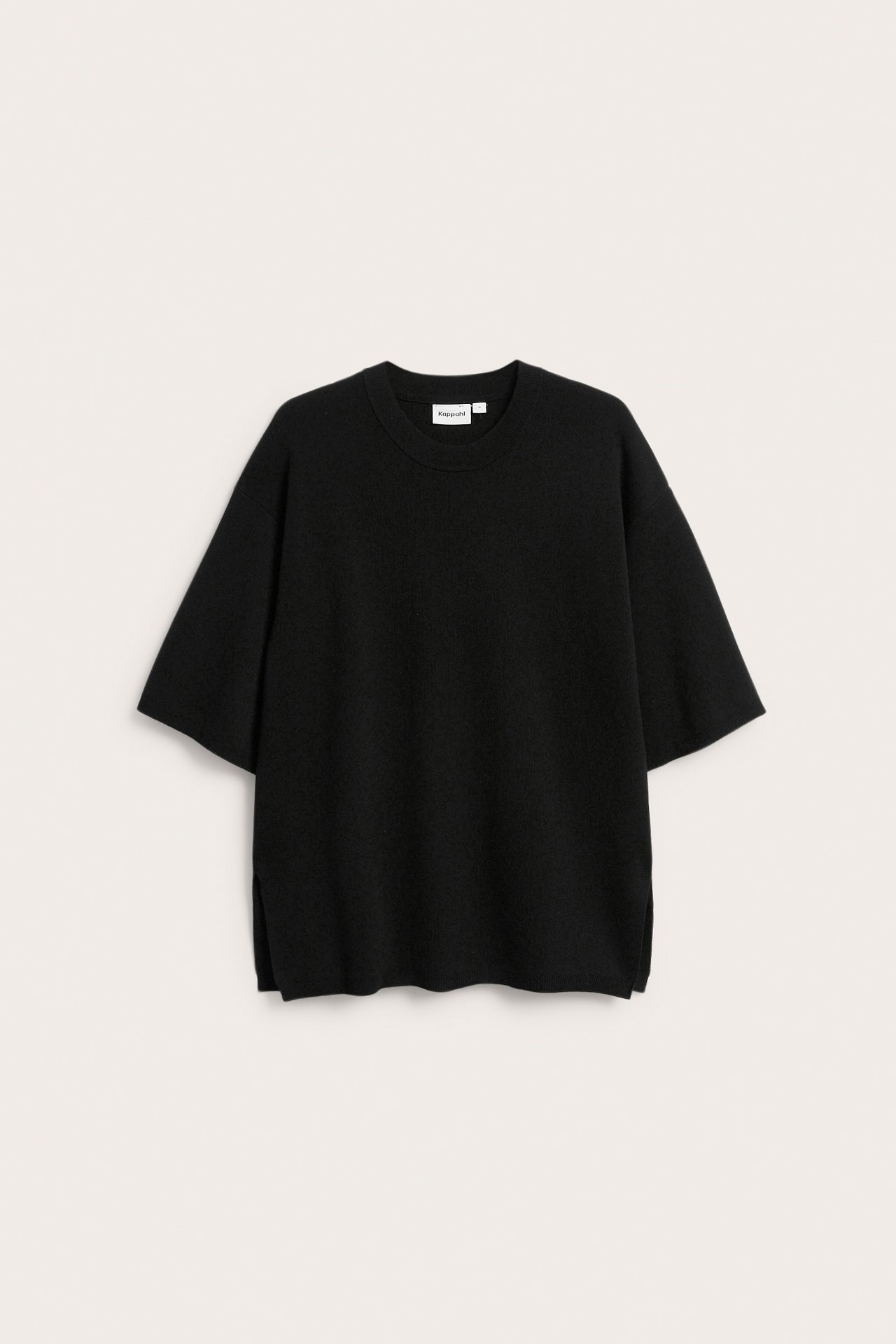 Edestäpäin löysä musta lyhythihainen hienoneulottu pusero, jossa on sivuhalkiot.