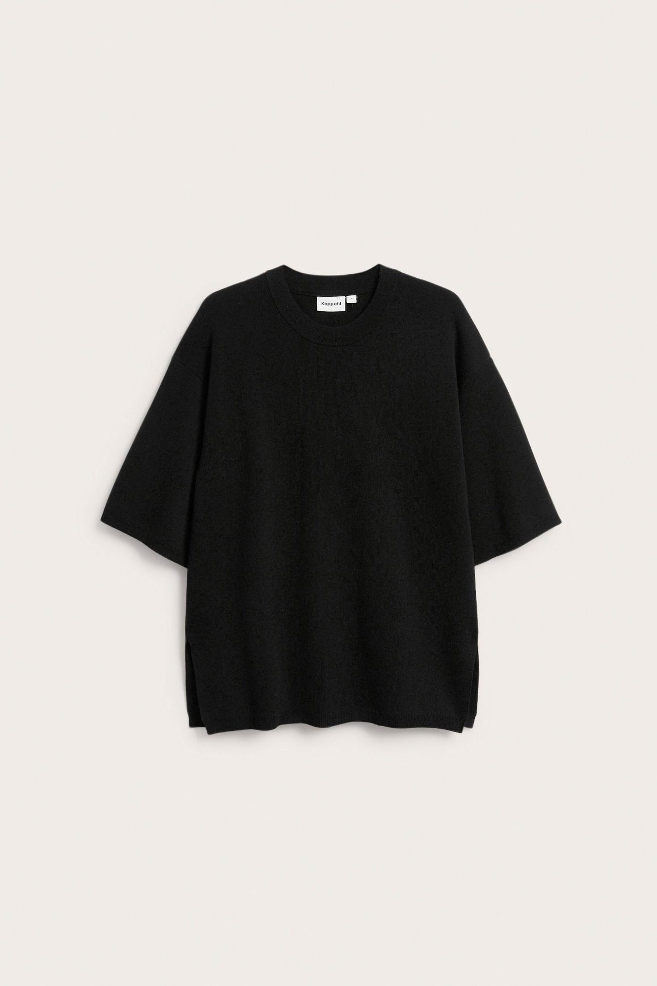 Edestäpäin löysä musta lyhythihainen hienoneulottu pusero, jossa on sivuhalkiot.