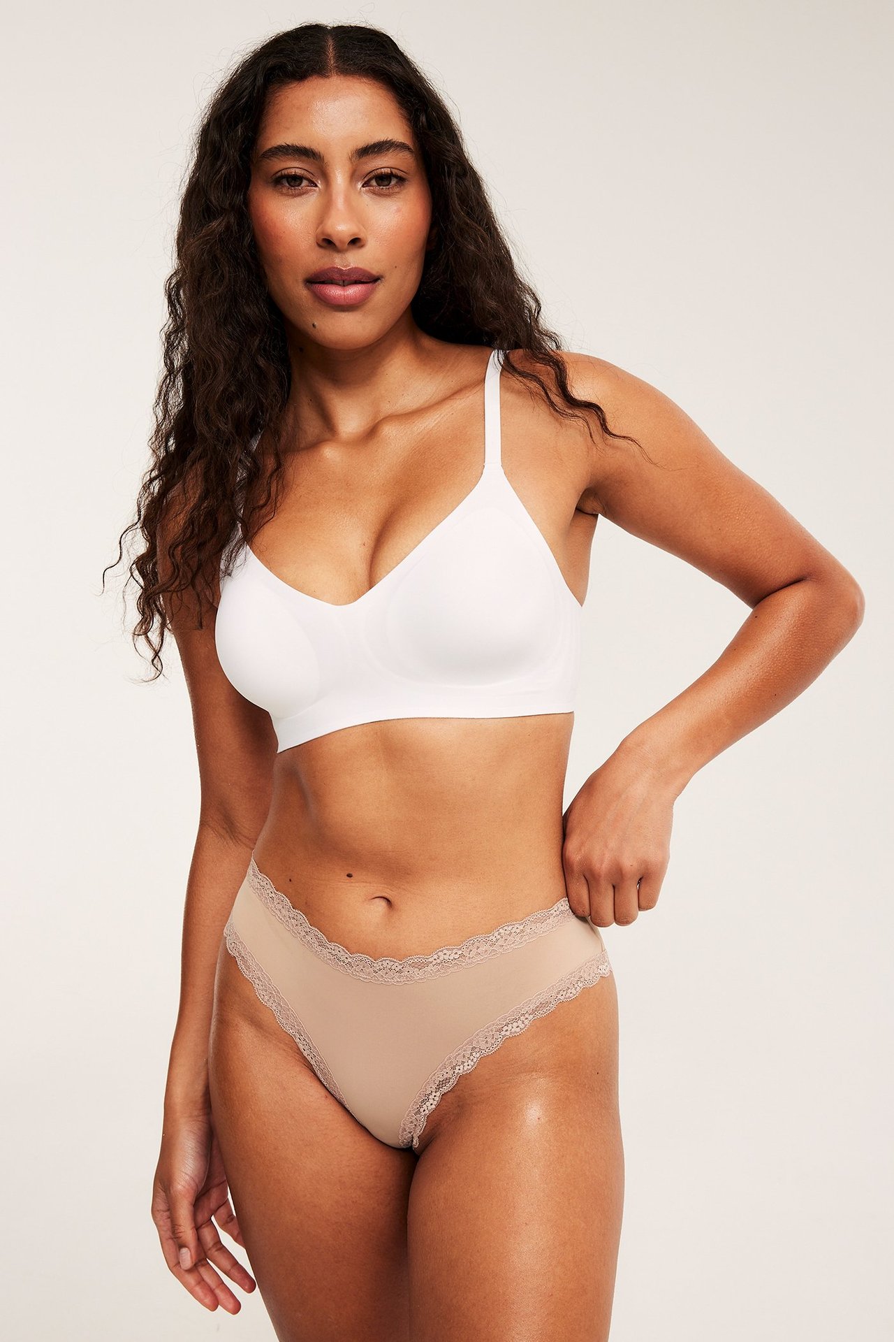 Forfra: kvinne i brune cheeky mikrofibertruser med blondekanter og en hvit BH.