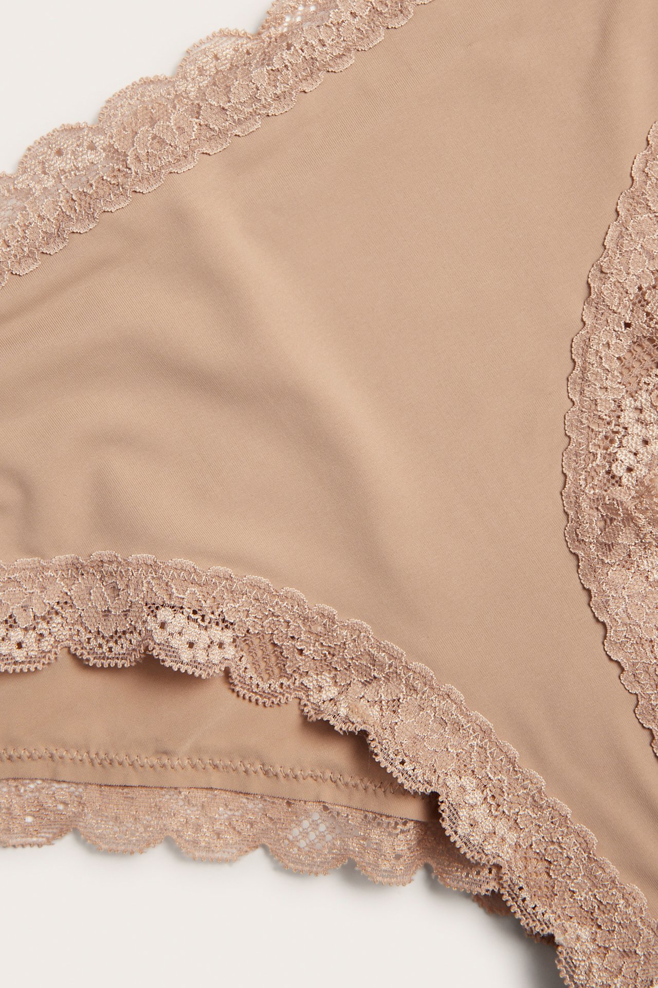 Närbild av bruna cheeky trosor i mjuk microkvalitet, med spetskanter vid midja och benöppningar.