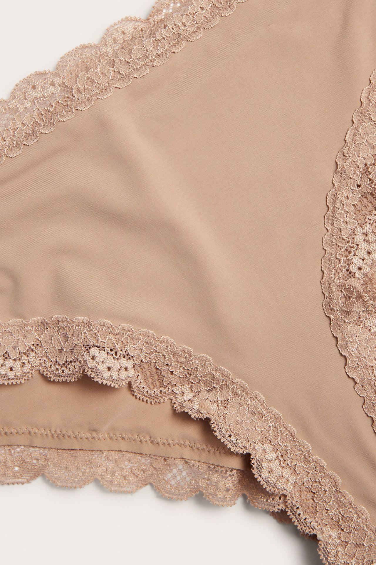 Lähikuva ruskeista cheeky-pikkuhousuista, pehmeää mikrokangasta ja pitsireunat vyötäröllä ja lahkeissa.