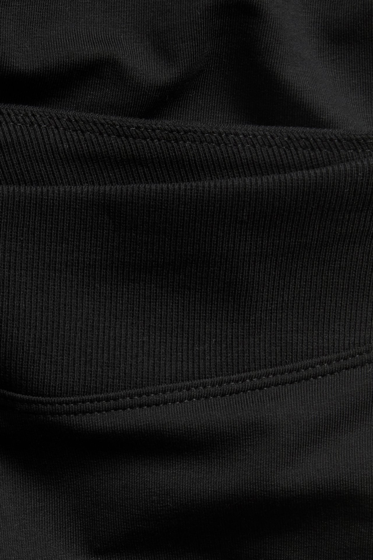 Zbliżenie czarnych legginsów typu flare, pokazujące prążkowany i gładki materiał bawełniano-elastanowy ze szwami.