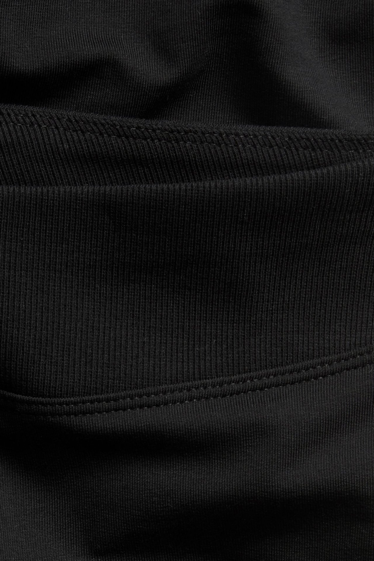 Zbliżenie czarnych legginsów typu flare, pokazujące prążkowany i gładki materiał bawełniano-elastanowy ze szwami.