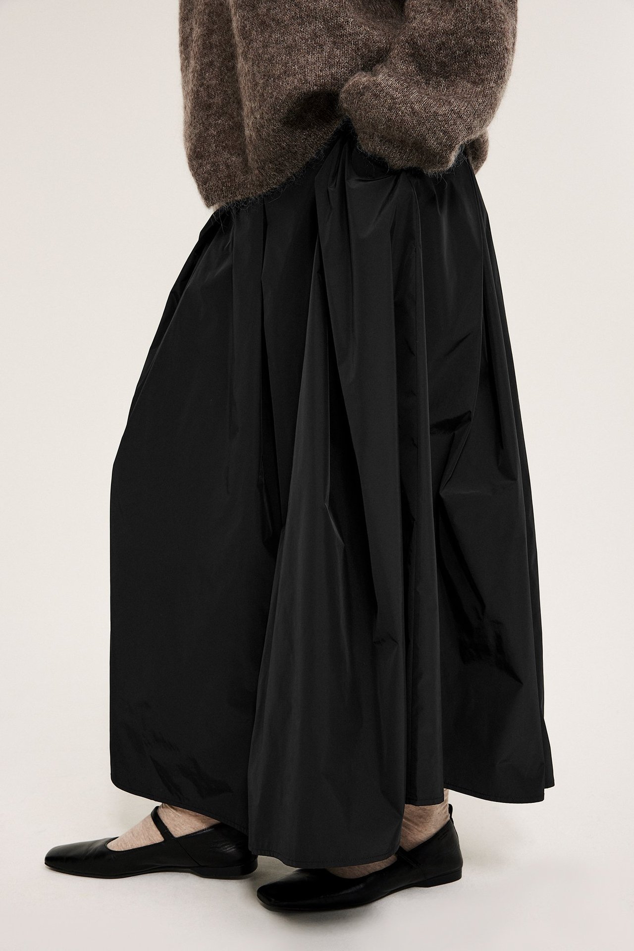 Svart midikjole med folder, fôr, sideglidelås, lommer, på kvinne.