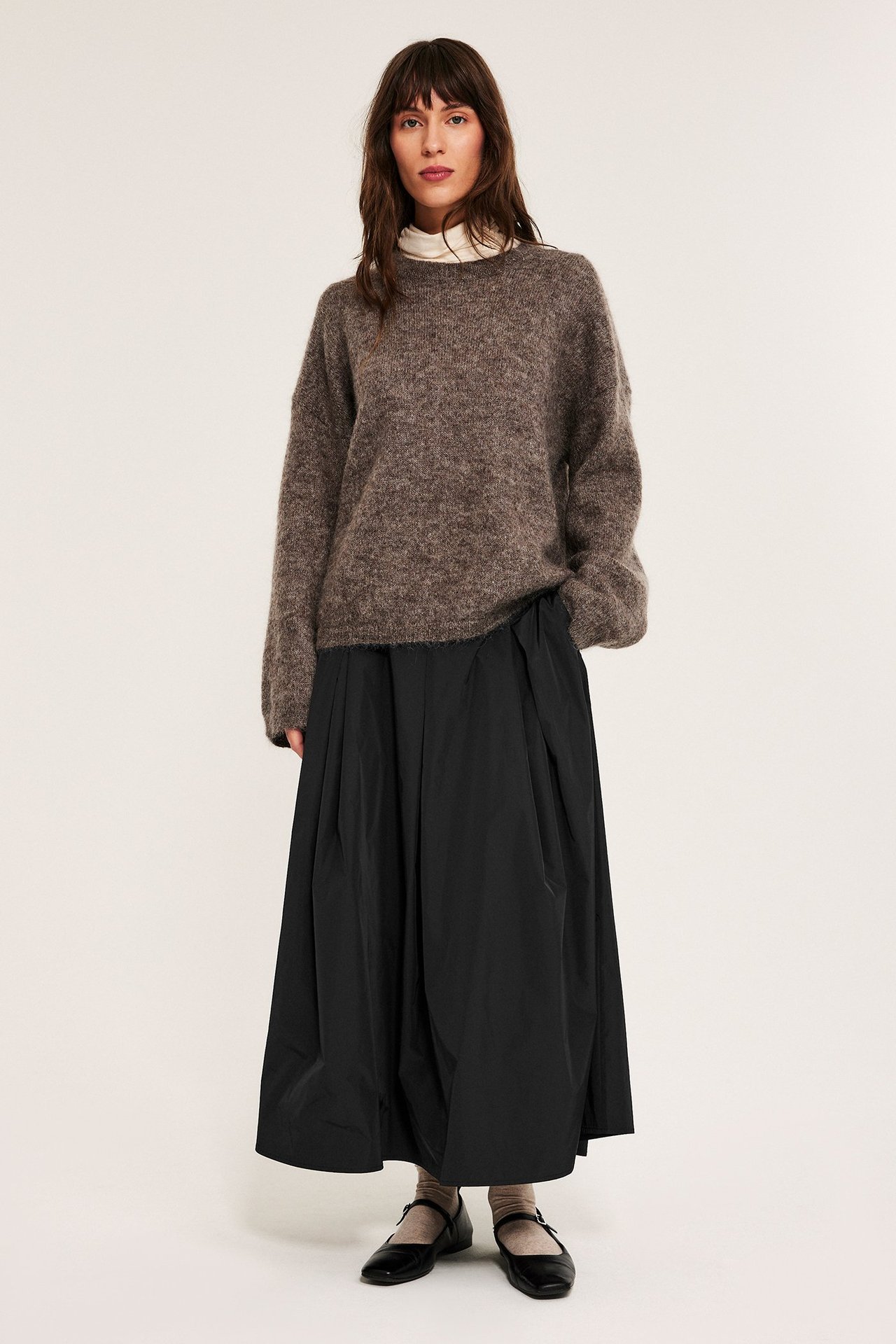 Svart midikjol med sideglidelås, foret polyester, sidelommer, brukt av kvinne.