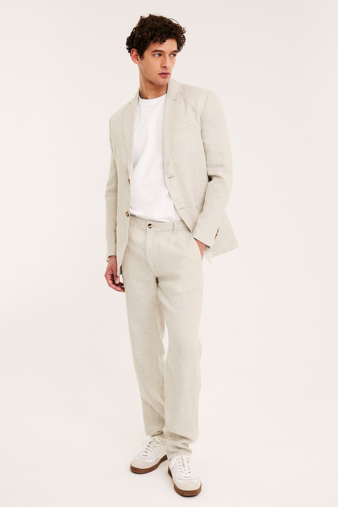 Forfra: Mann i beige regular fit linneblazer over hvit t-skjorte, matchende bukser og hvite sneakers.