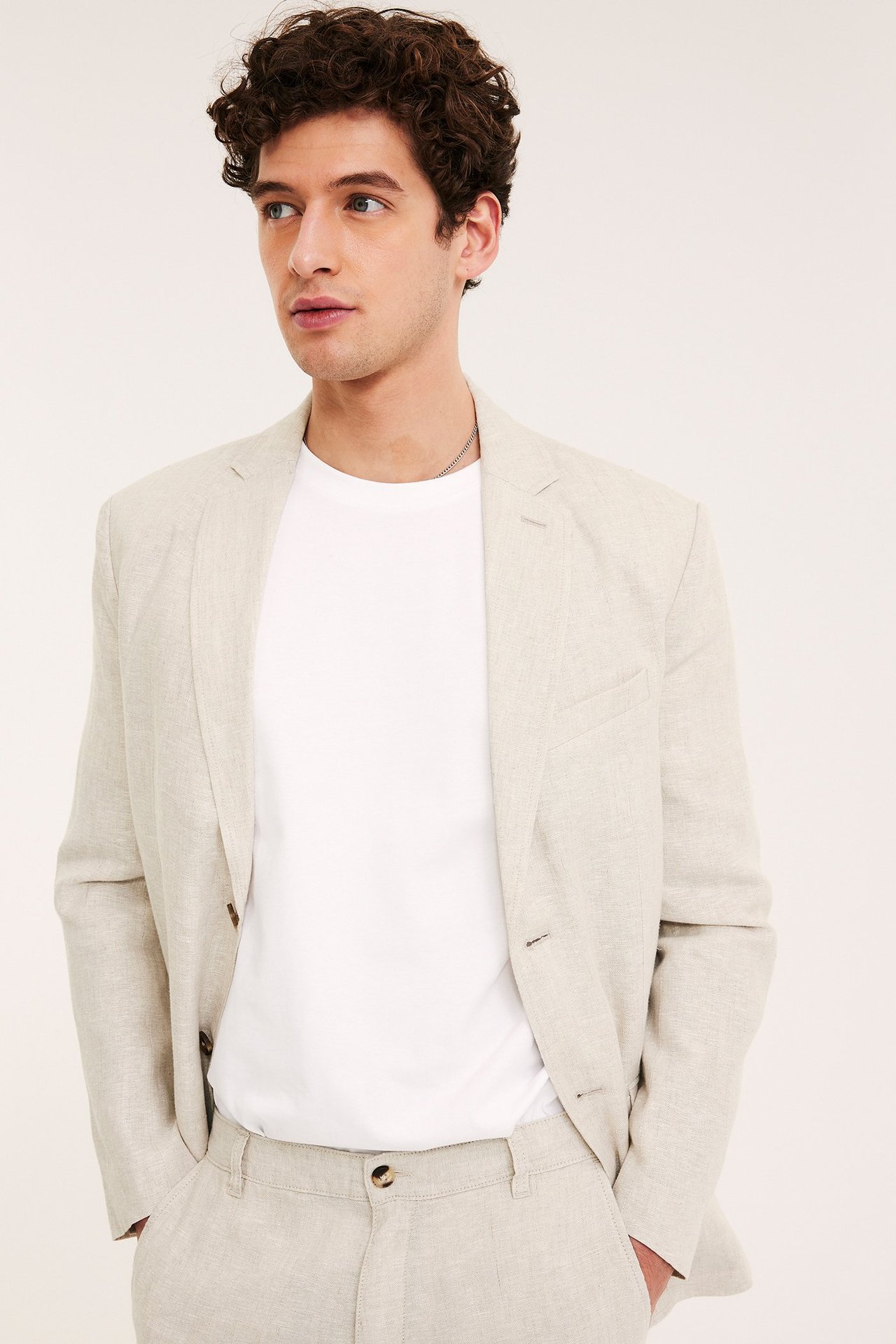 Frontbilde av en mann i en beige regular fit linkavaj over hvit t-skjorte og matchende bukser.