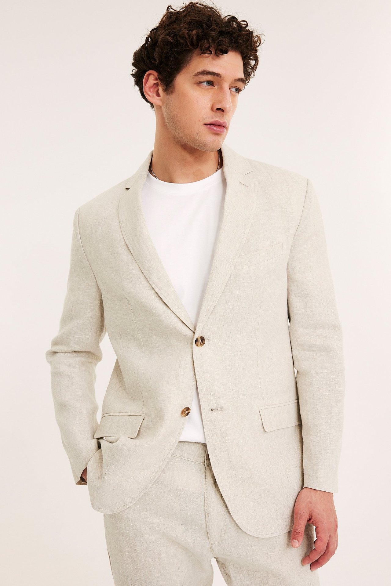 Mies edestä, yllään beige regular fit pellavableiseri, valkoinen t-paita ja yhteensopivat pellavahousut.