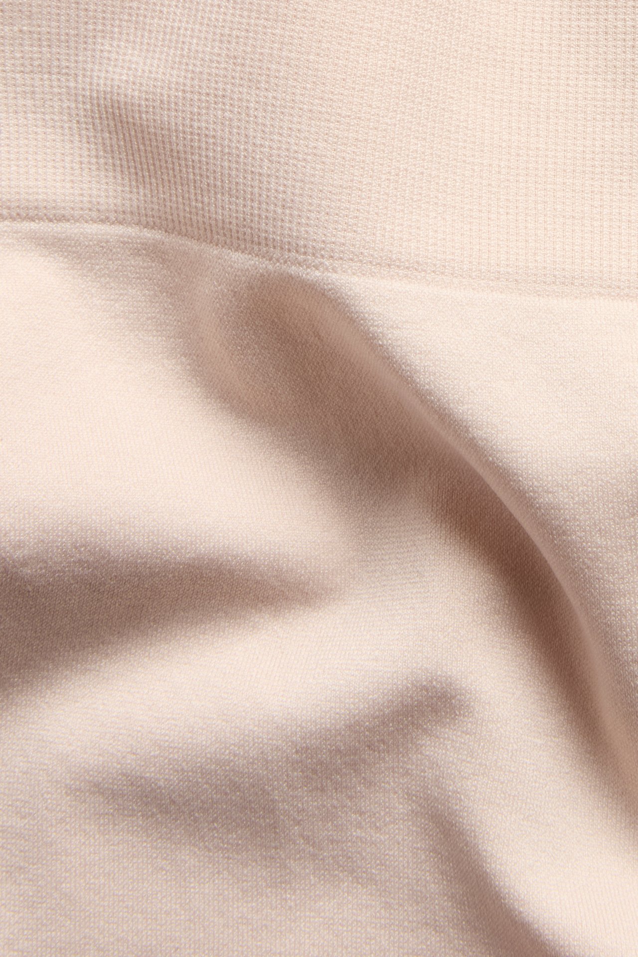 Lähikuva vaaleanpunaisista saumattomista shortseista, joissa sileä kangas ja uurrettu yläreuna.