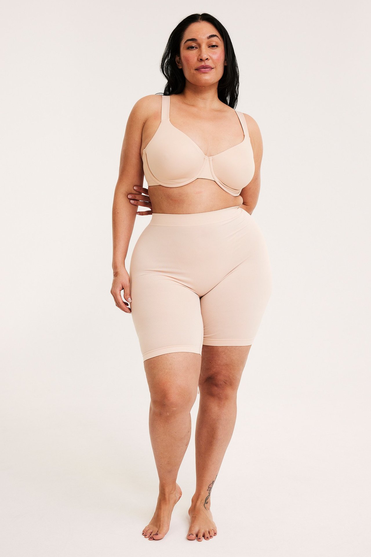 Widok z przodu kobiety w jasnoróżowych bezszwowych szortach i pasującym biustonoszu.