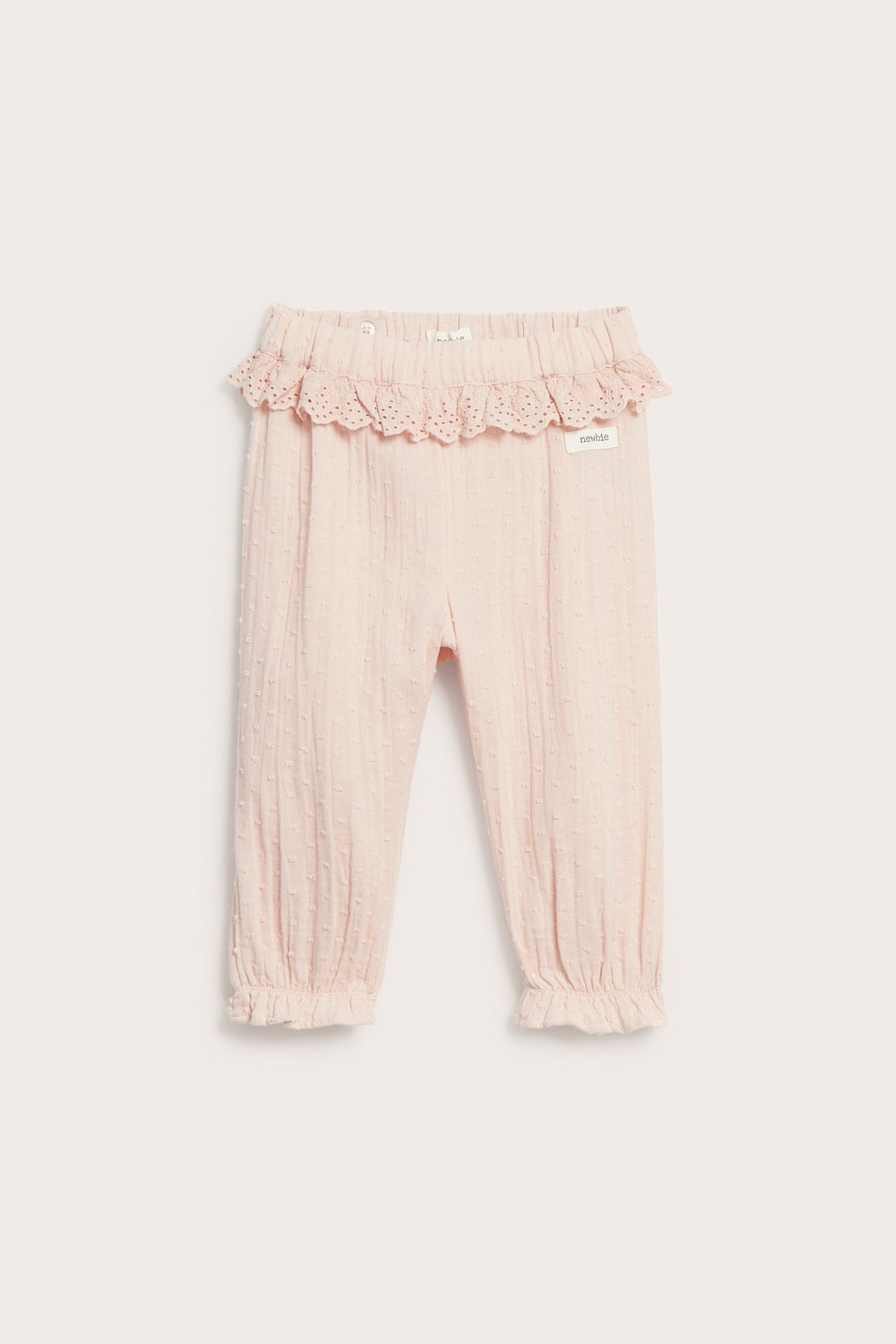 Front: Lys rosa bomullsbukse for barn med prikkstruktur, blondepyntet elastisk midje og rysjer ved bena.