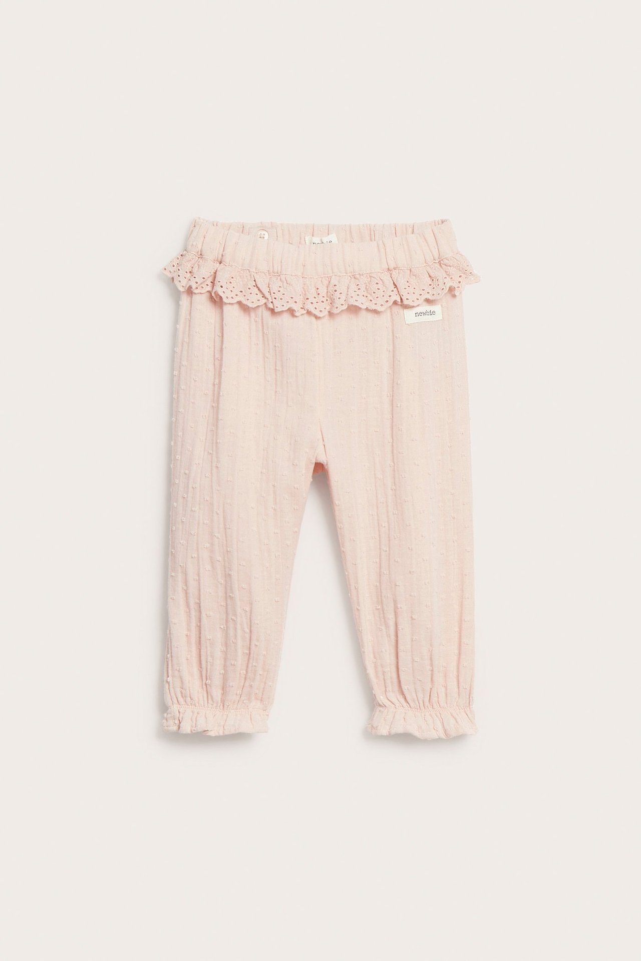 Front: Lys rosa bomullsbukse for barn med prikkstruktur, blondepyntet elastisk midje og rysjer ved bena.