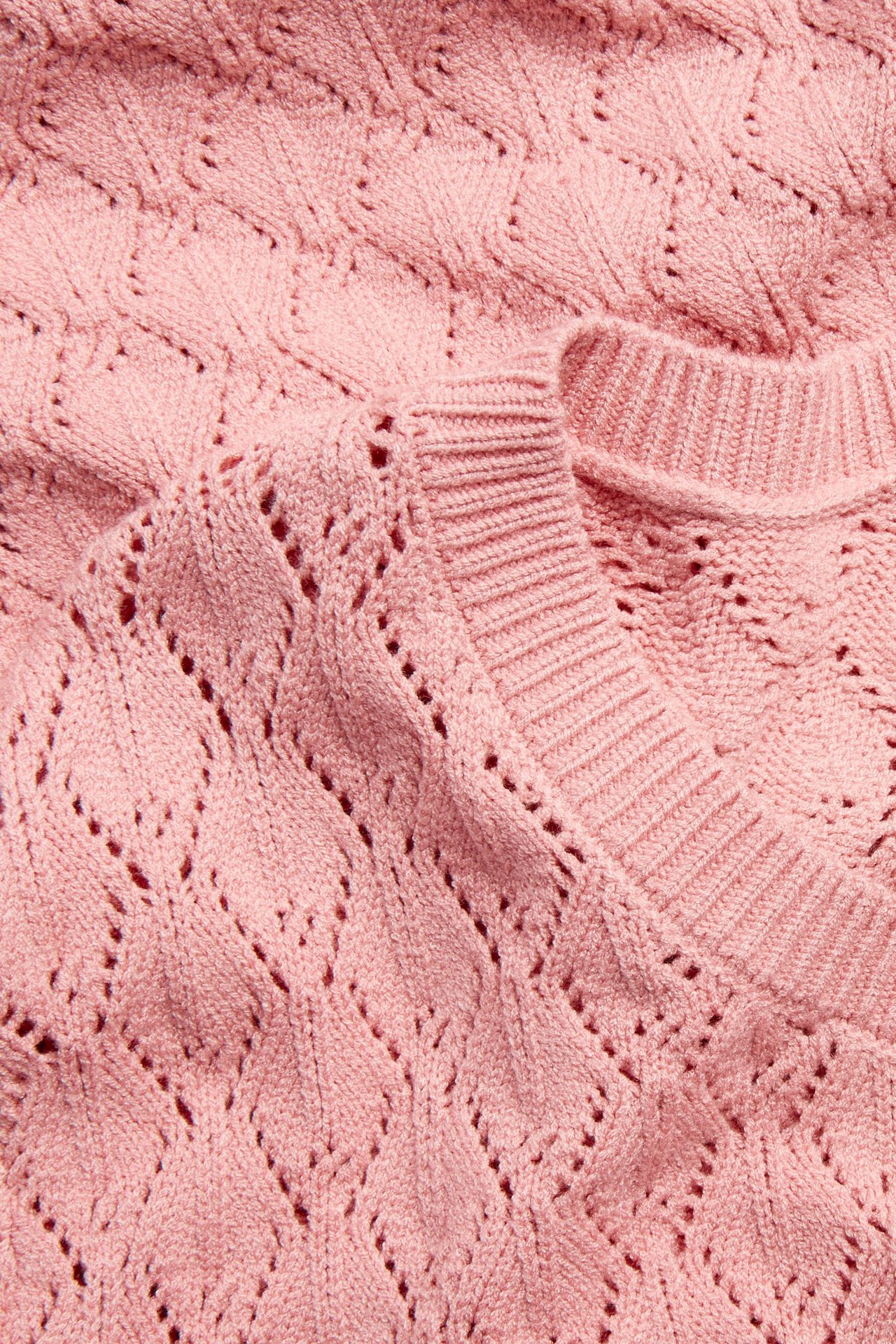 Nærbilde av en rosa hullstrikket t-skjorte med rund hals.