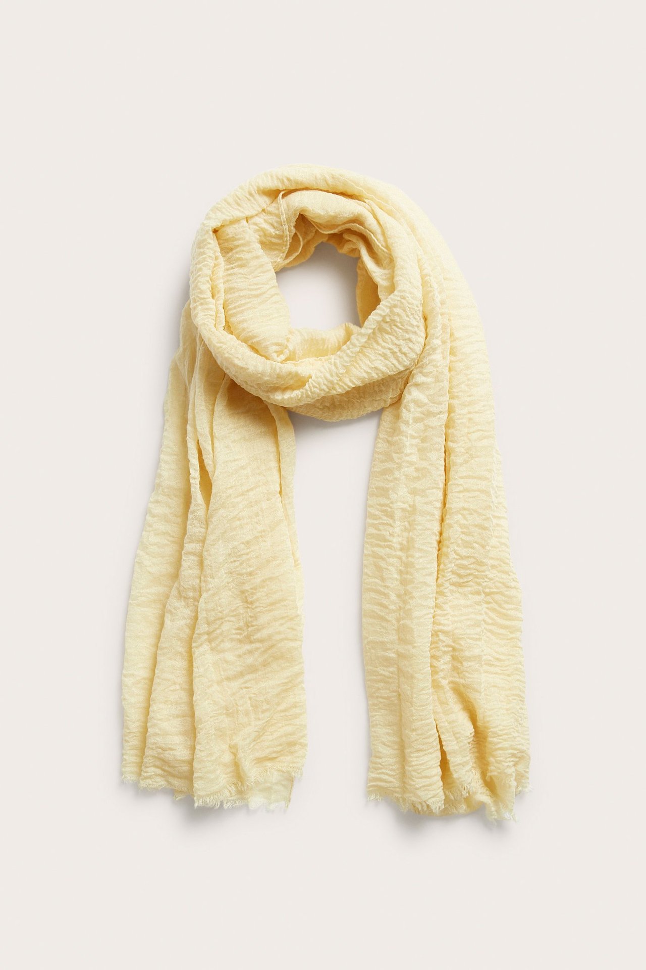 Framifrån, en draperad, gul krinklad polyestersjal med fransade ändar.