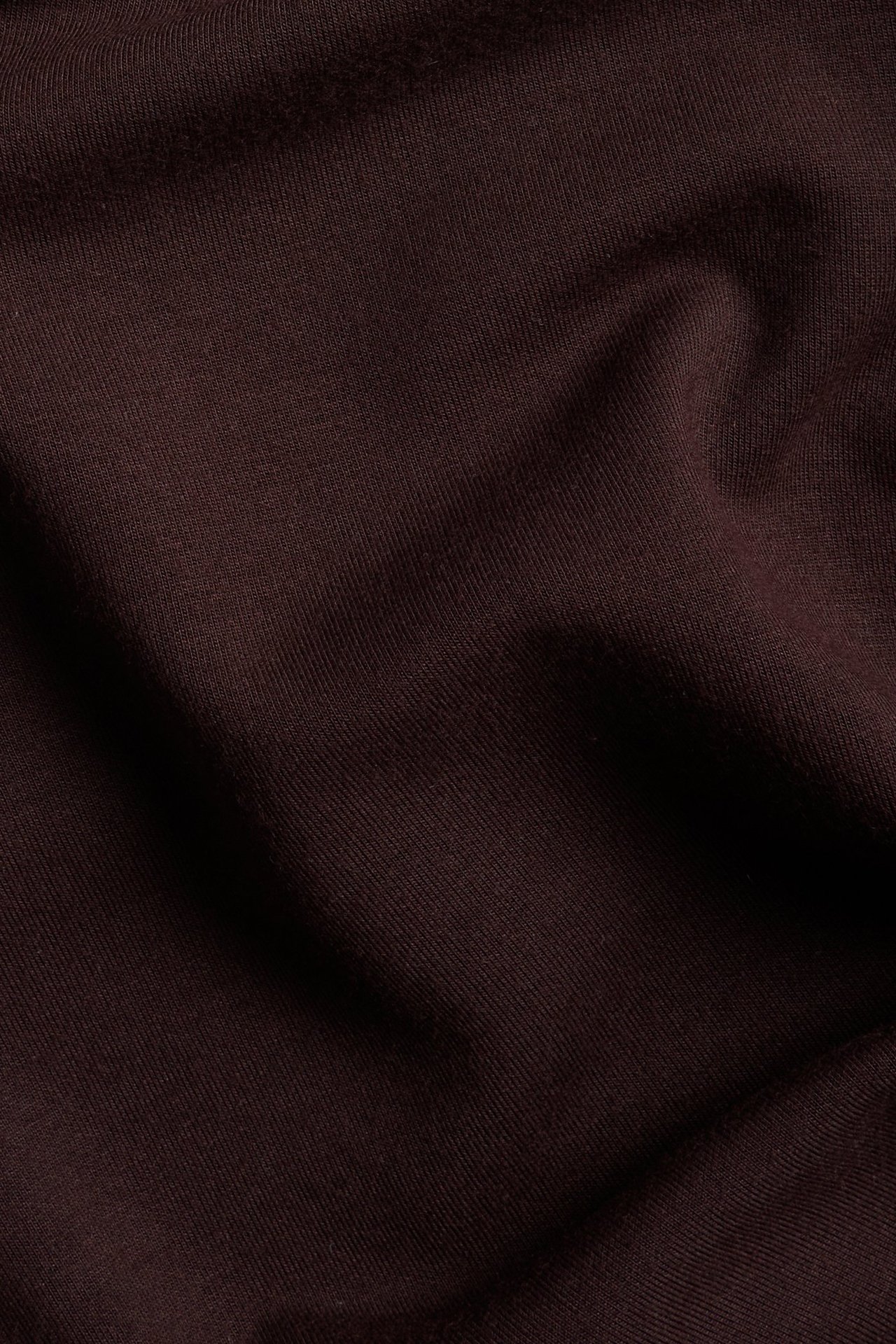 Zbliżenie na bordową tkaninę długiej sukienki z miękkim drapowaniem.