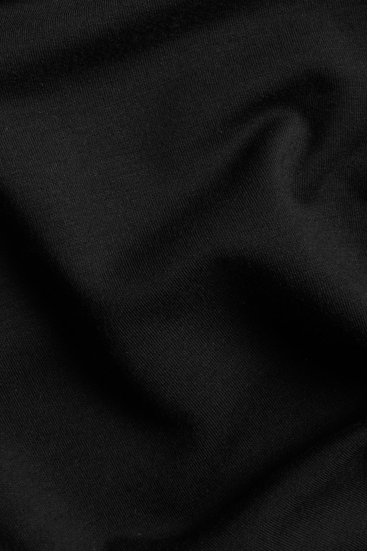 Zbliżenie na czarny, jednolity materiał długiej sukienki, ukazujące miękkie fałdy.