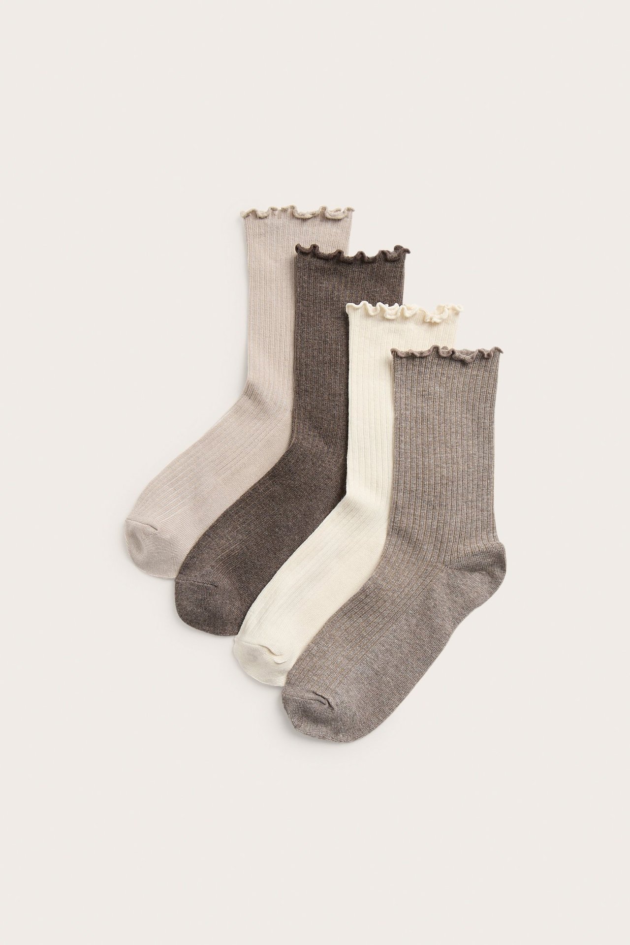 Widok z przodu czterech par prążkowanych skarpet bawełnianych: jasnobeżowych, ciemnobrązowych, ecru i szarobrązowych, z falbanką.