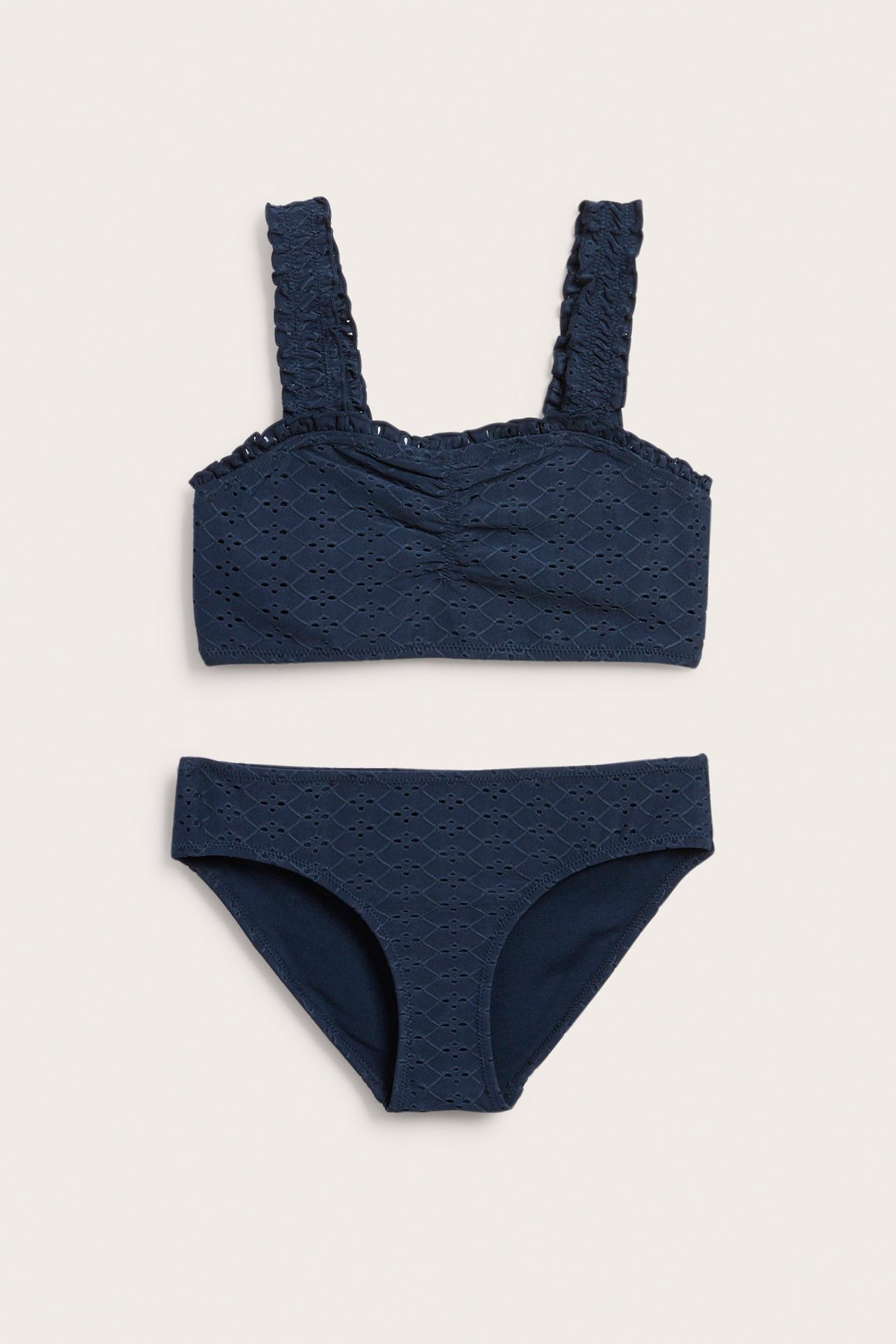 Edestä kuvattu lasten sininen broderie anglaise bikini, jossa röyhelöolkaimet ja rypytetty yläosa.