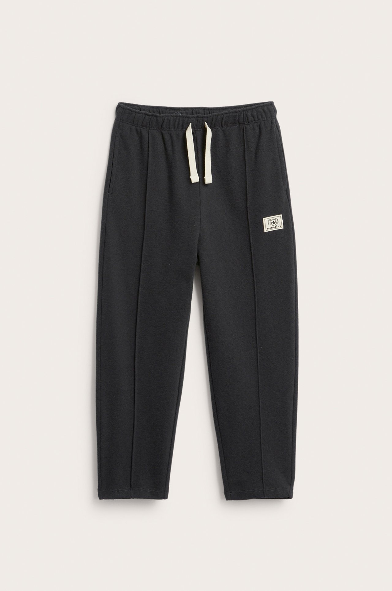 Framifrån: svarta mjukisbyxor i strukturerad bomull med resår i midjan och beige dragsko.