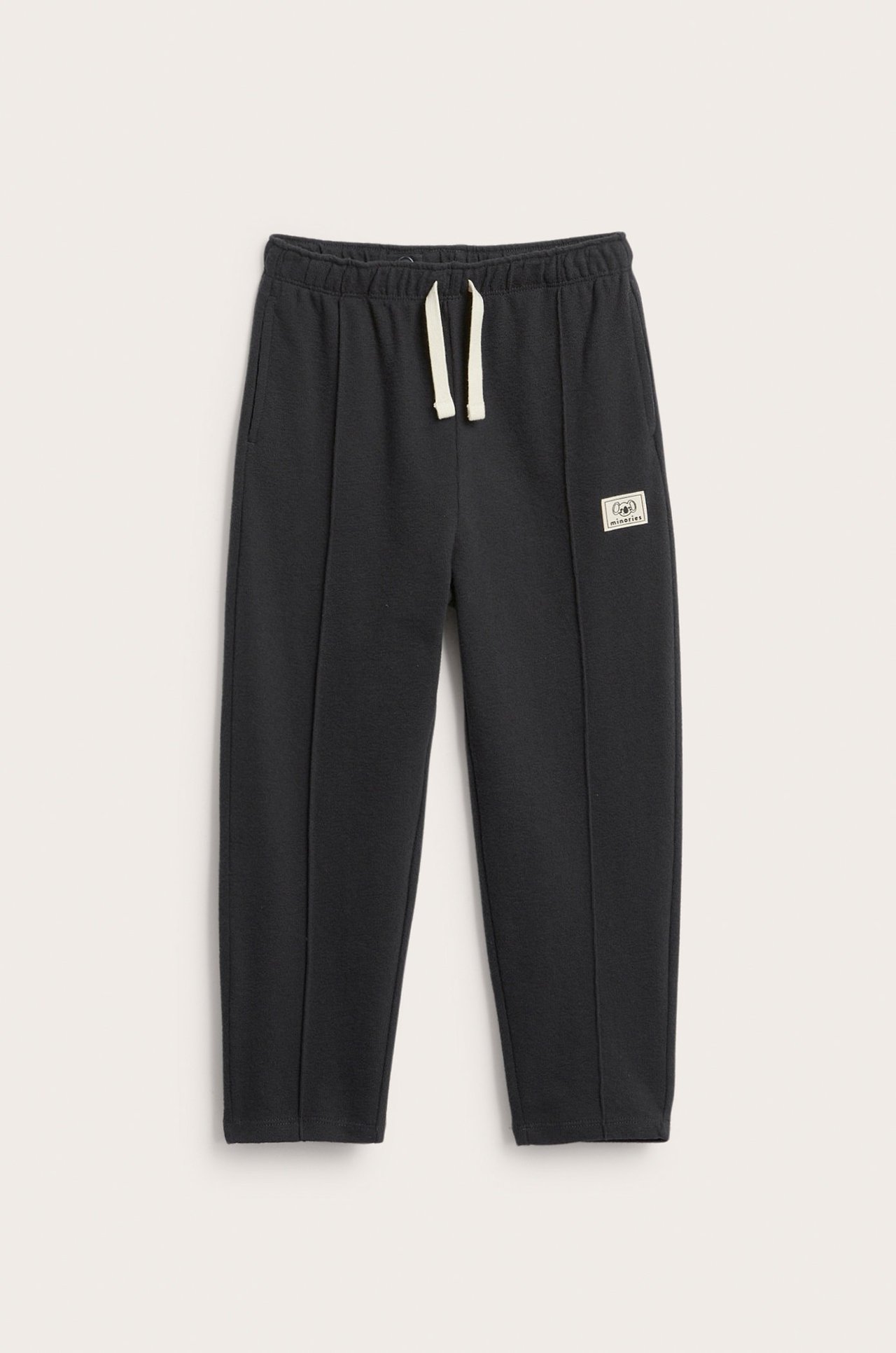 Edestäpäin: mustat collegehousut kuvioidusta puuvillasta, joustava vyötärö ja beige nyöri.