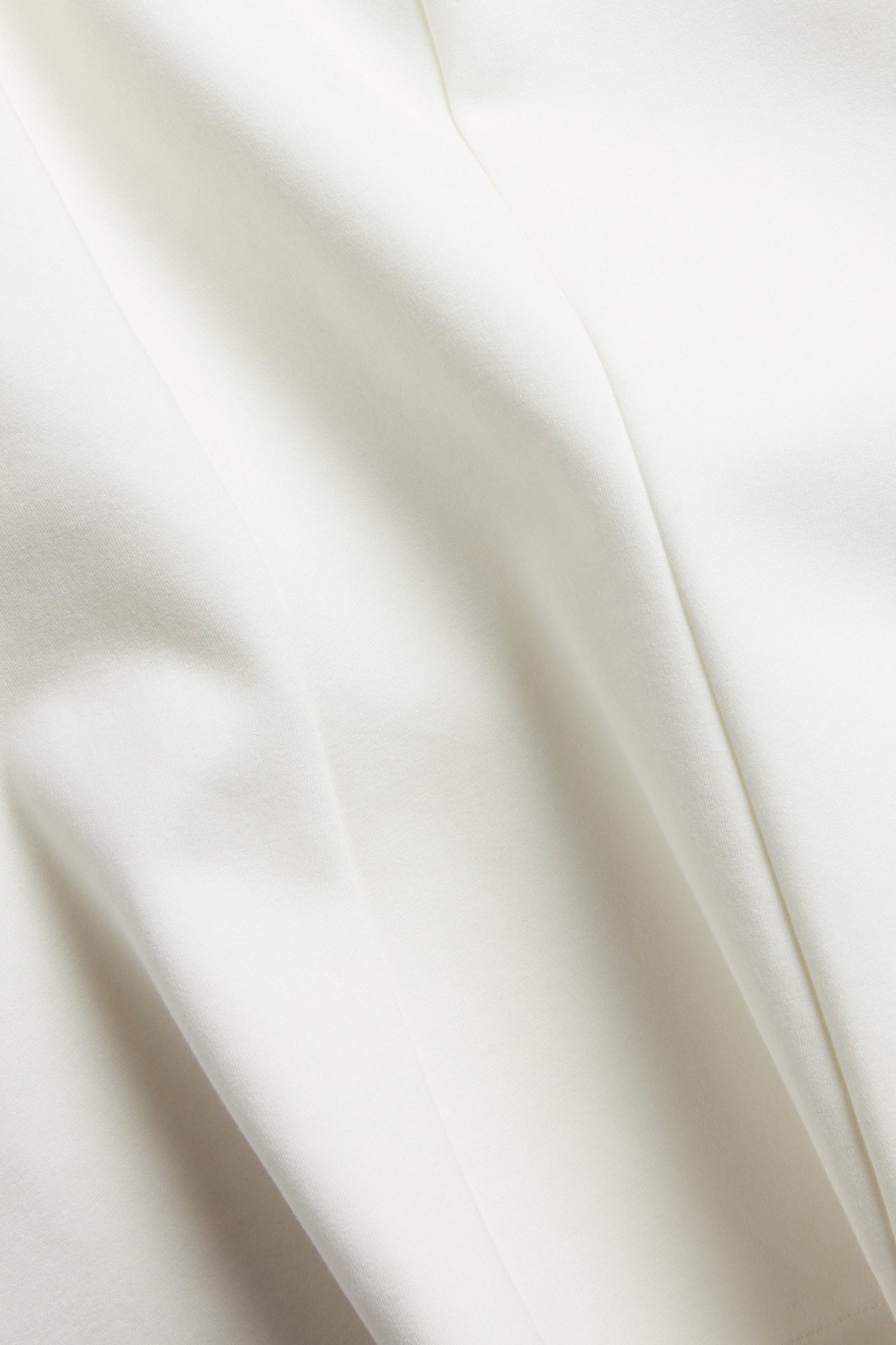 Zbliżenie na jednolity, kremowobiały materiał z mieszanki wiskozy, ukazujący miękkie fałdy i teksturę.