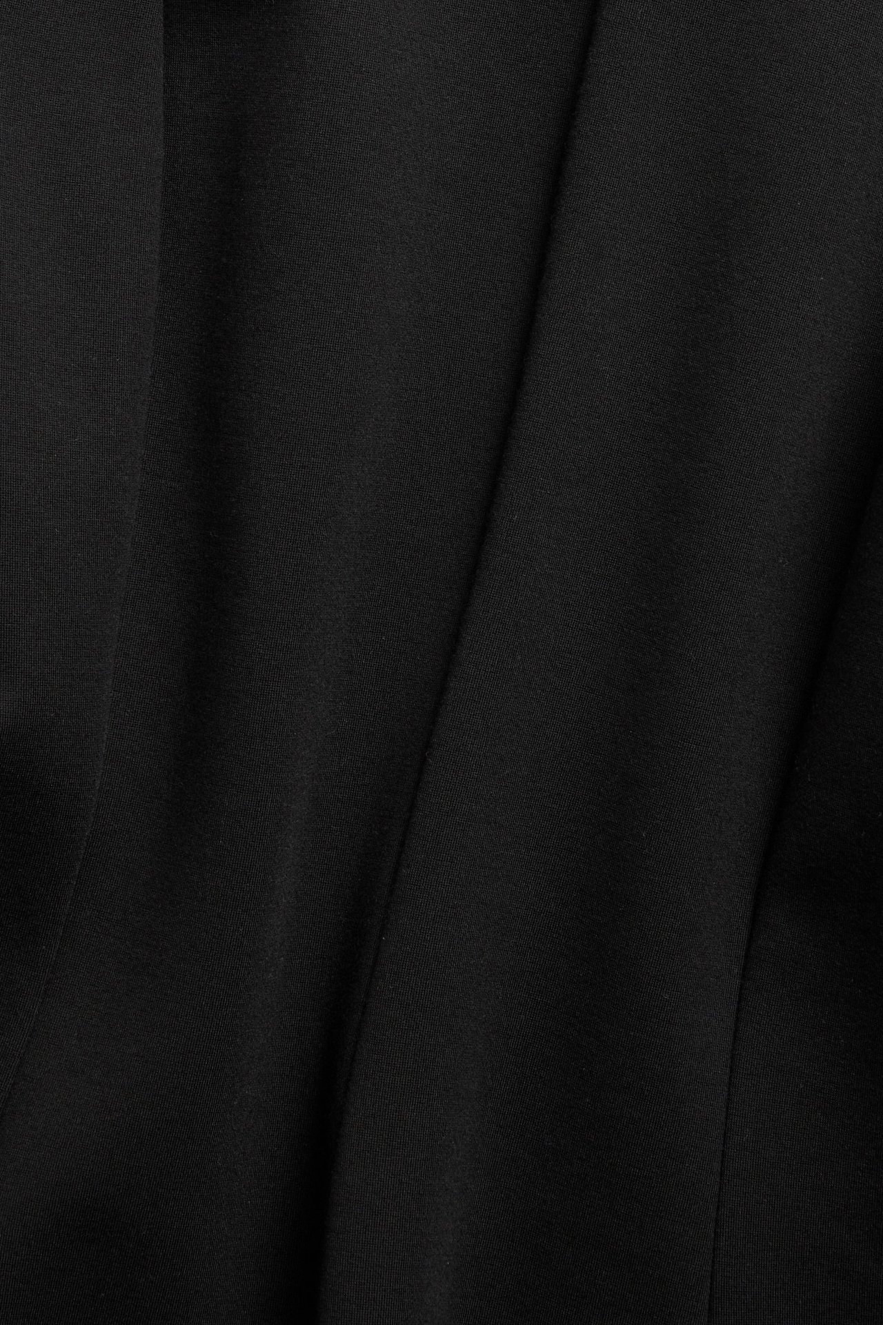 Zbliżenie na czarną, jednolitą tkaninę z mieszanki wiskozy przeznaczoną na bluzkę peplum.