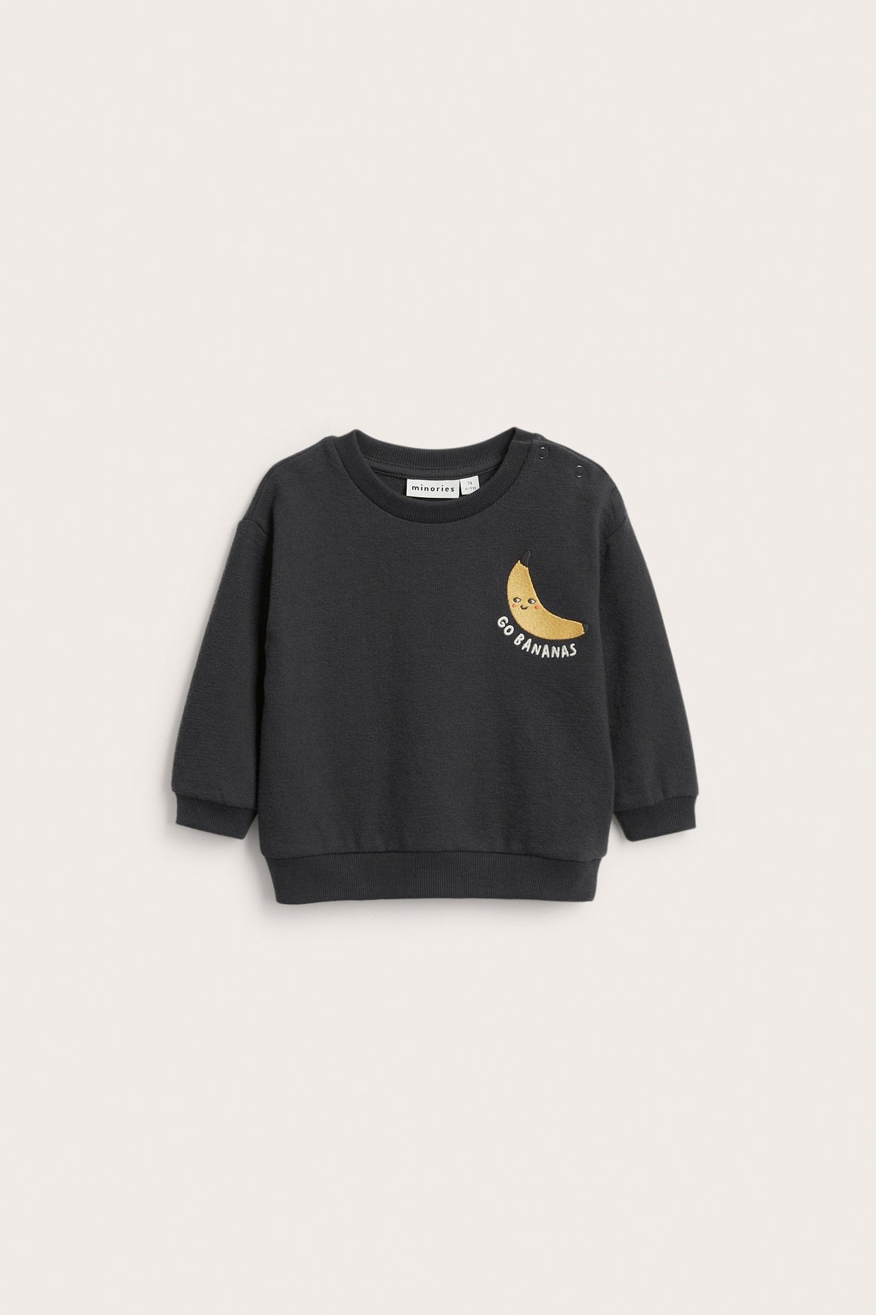 Edestä tummanharmaa vauvan collegepaita keltaisella banaanikirjailulla ja olkapään painonapeilla.