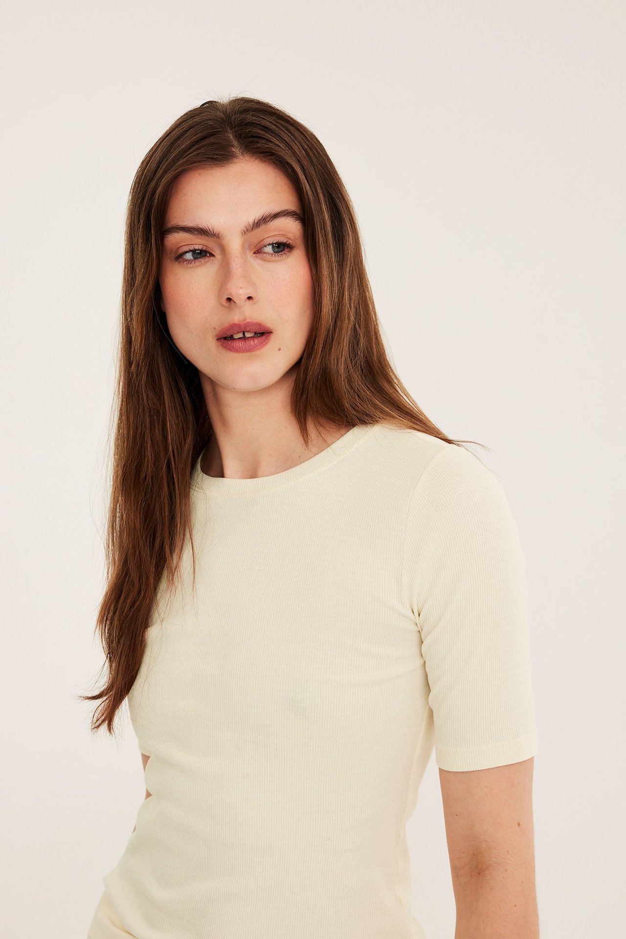 Edestäpäin, nainen yllään istuva luonnonvalkoinen ribbineuleinen lyhythihainen toppi.