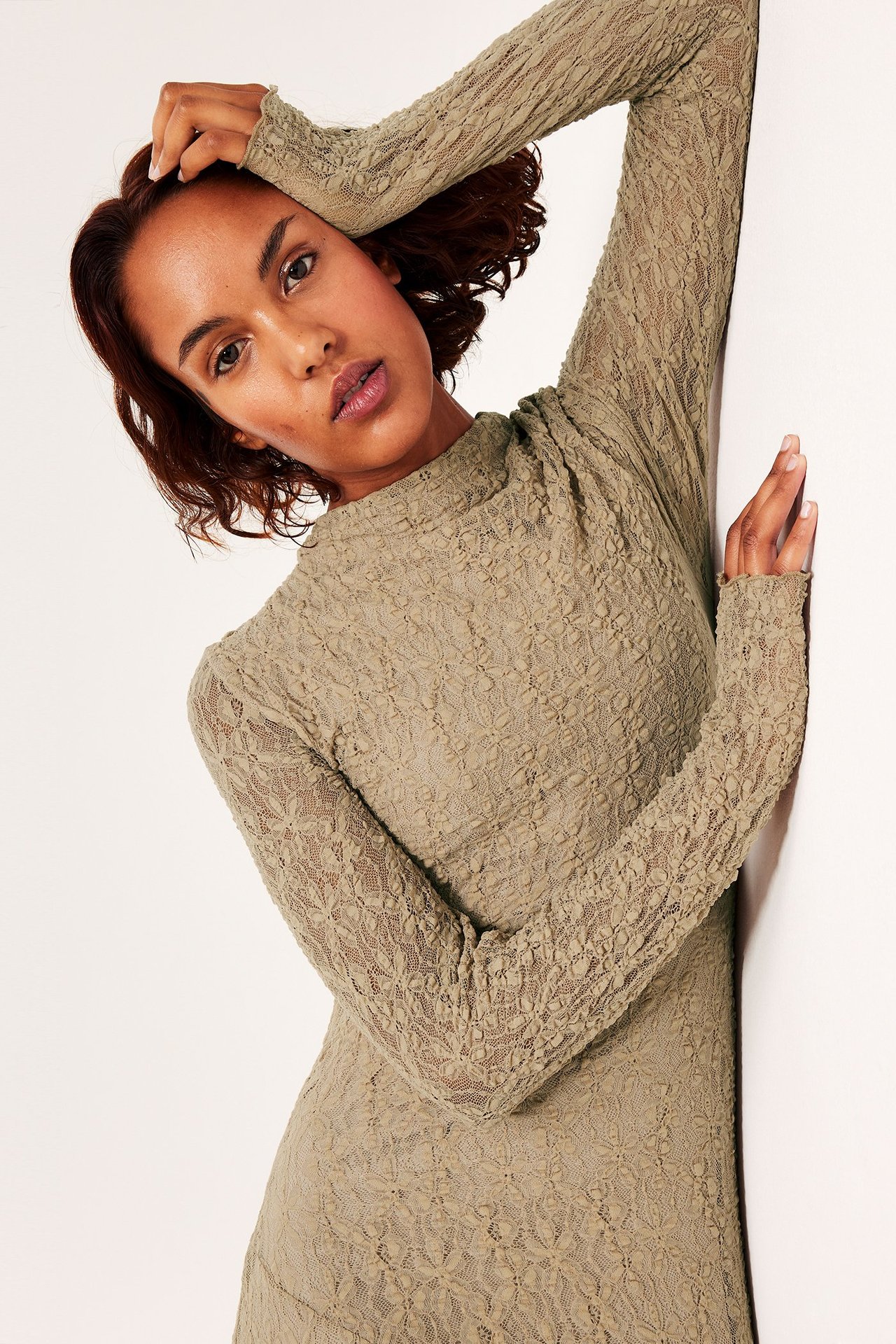 Asymmetrisen beigen pitsimekko, pitkähiha, naisella, muotoileva istuvuus.