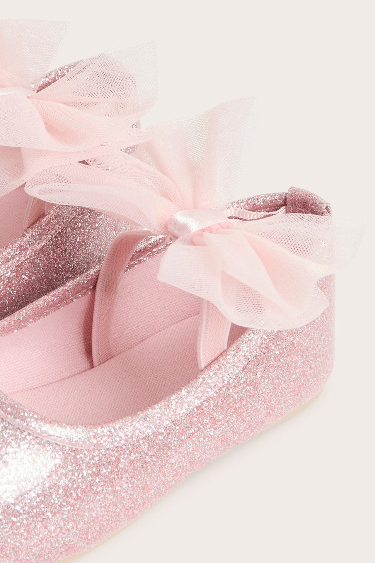 Widok z boku jasnoróżowych brokatowych balerinek z kokardą z siateczki.