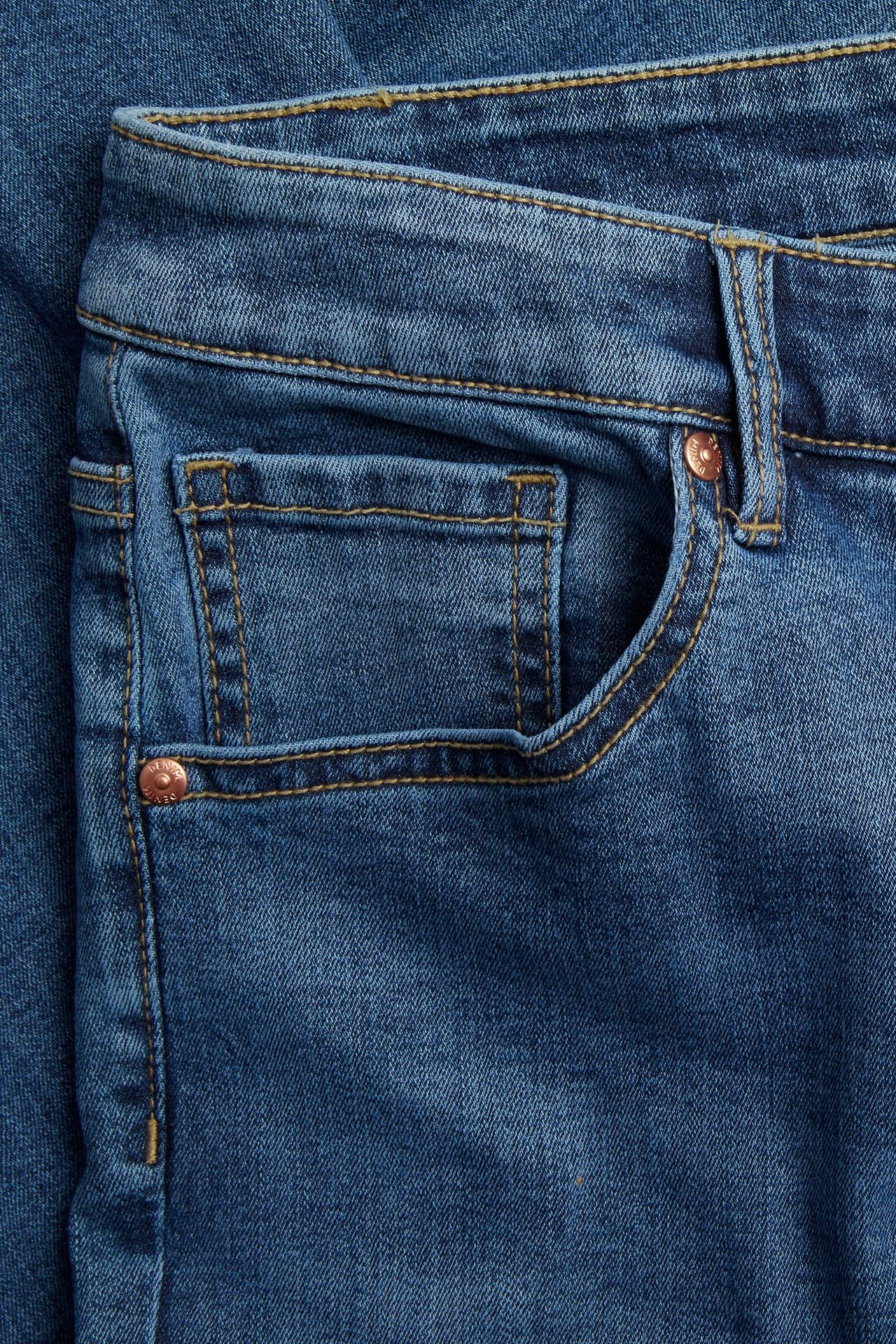 Zbliżenie przodu: niebieskie dżinsy cropped flare z kieszenią, pomarańczowymi przeszyciami, miedzianymi nitami.