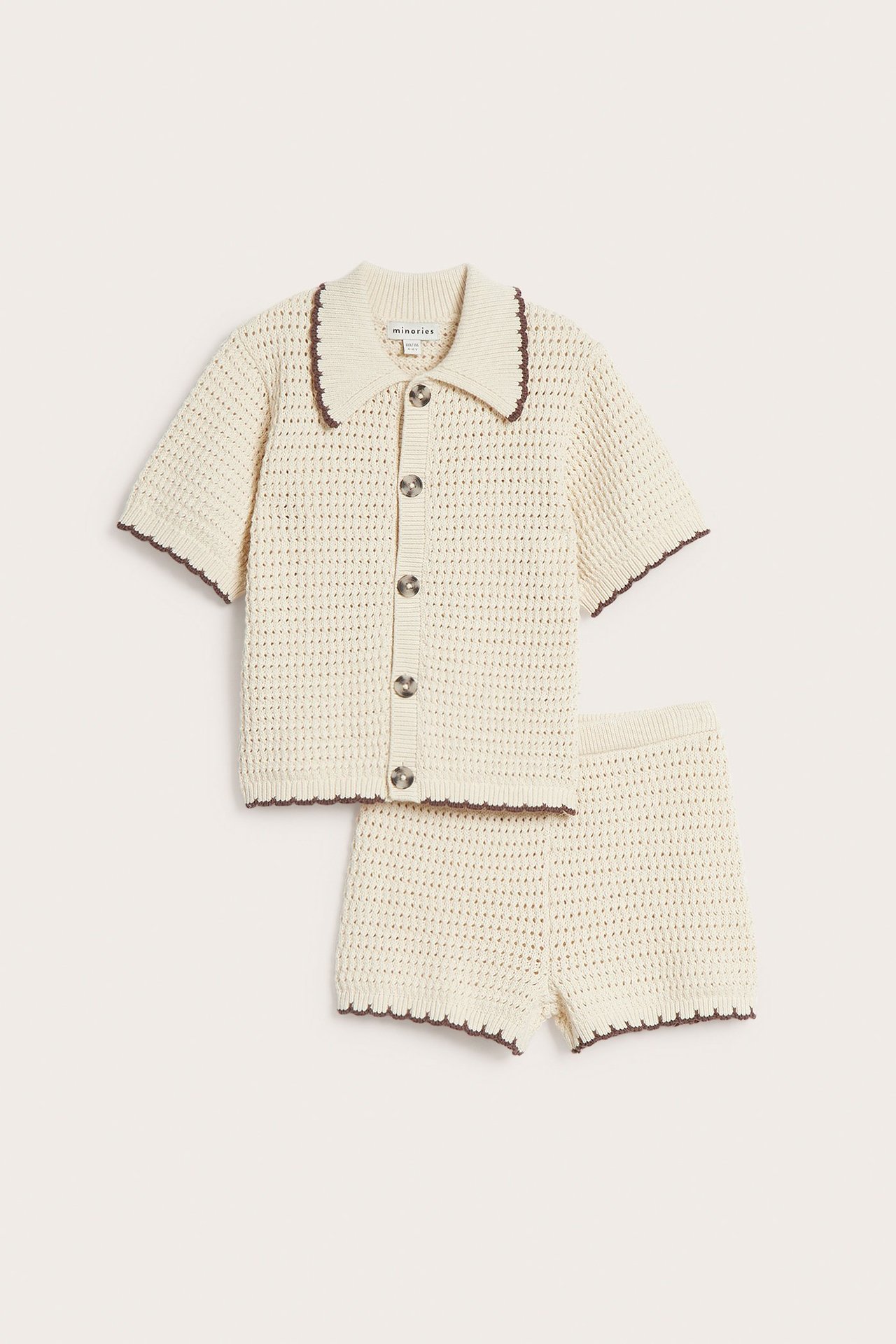 Front view: Barns beige strikkede bomullssett: kortermet kragetopp med knapper, brun kant, matchende shorts.