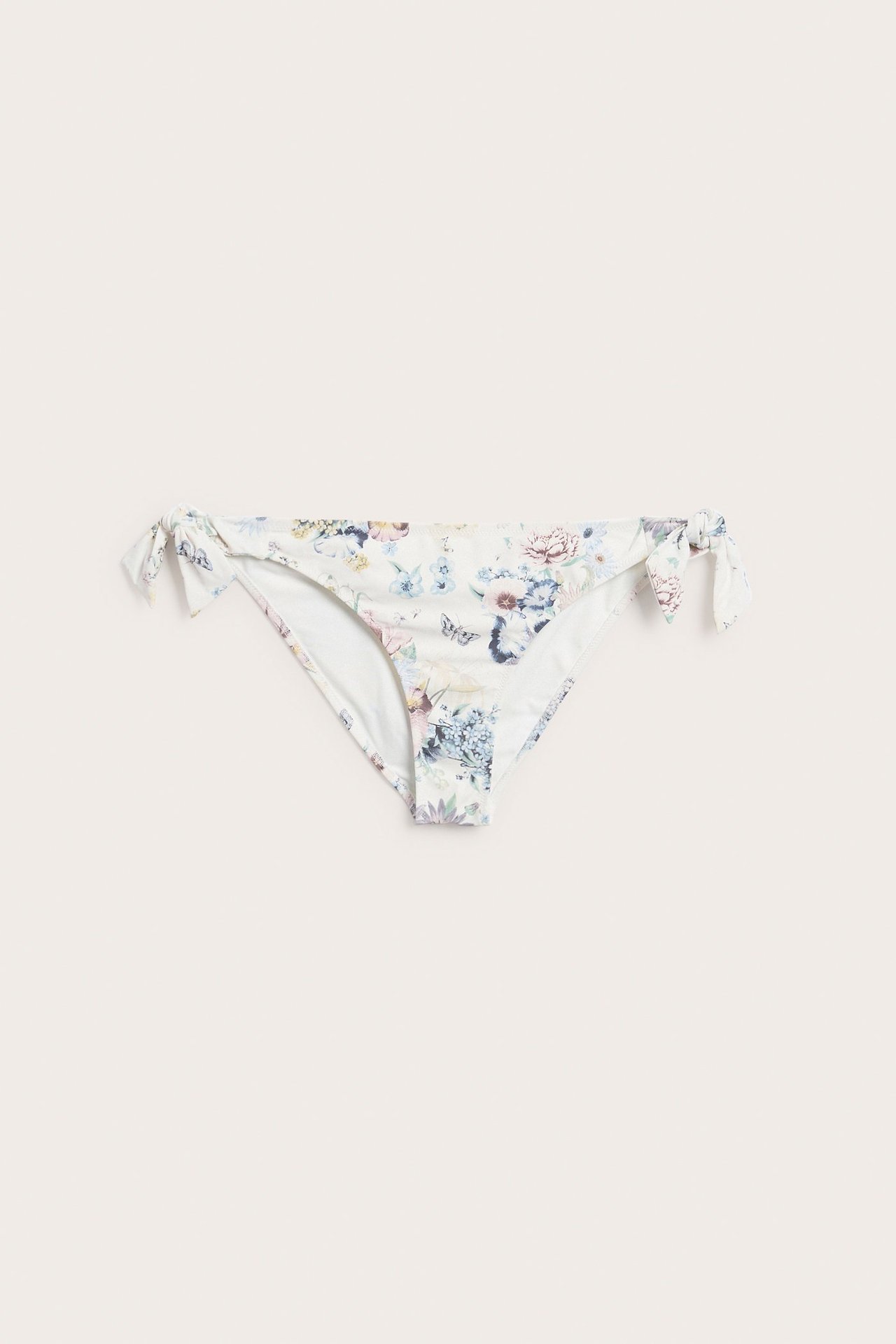 Framifrån, offwhite blommig brazilian bikinitrosa med knytband i sidorna.