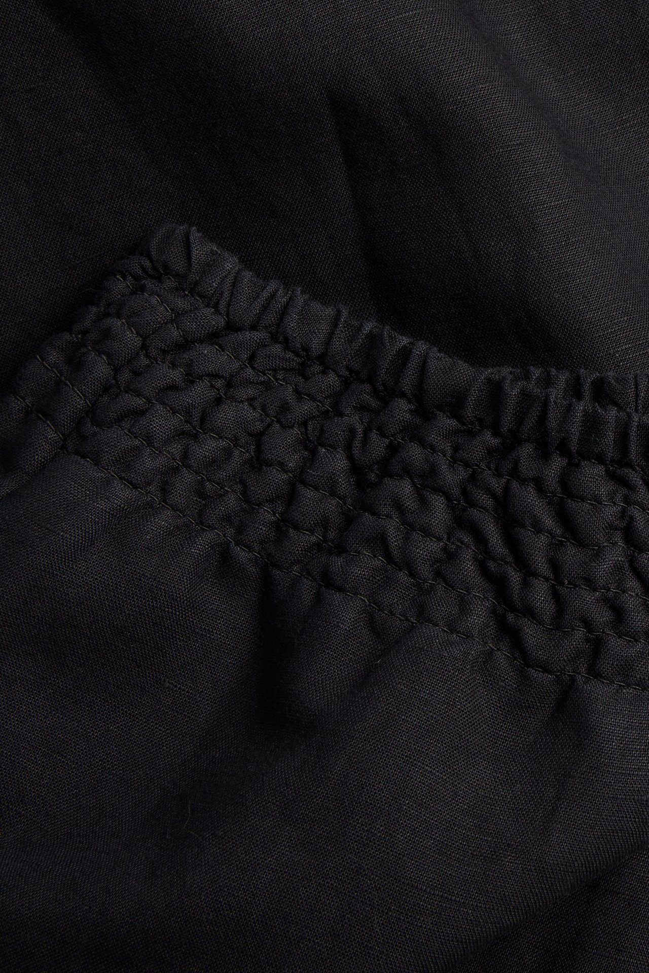 Zbliżenie czarnych spodni z domieszką lnu ze ściągaczem w pasie.