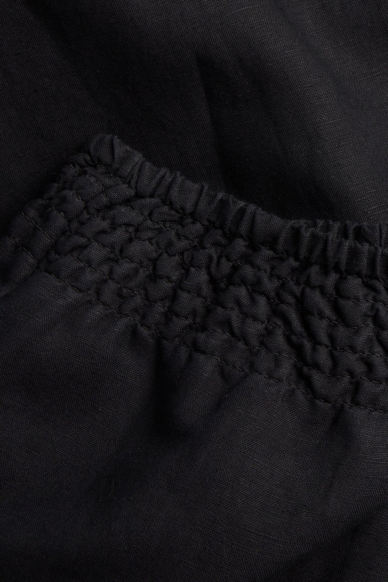 Zbliżenie czarnych spodni z domieszką lnu ze ściągaczem w pasie.