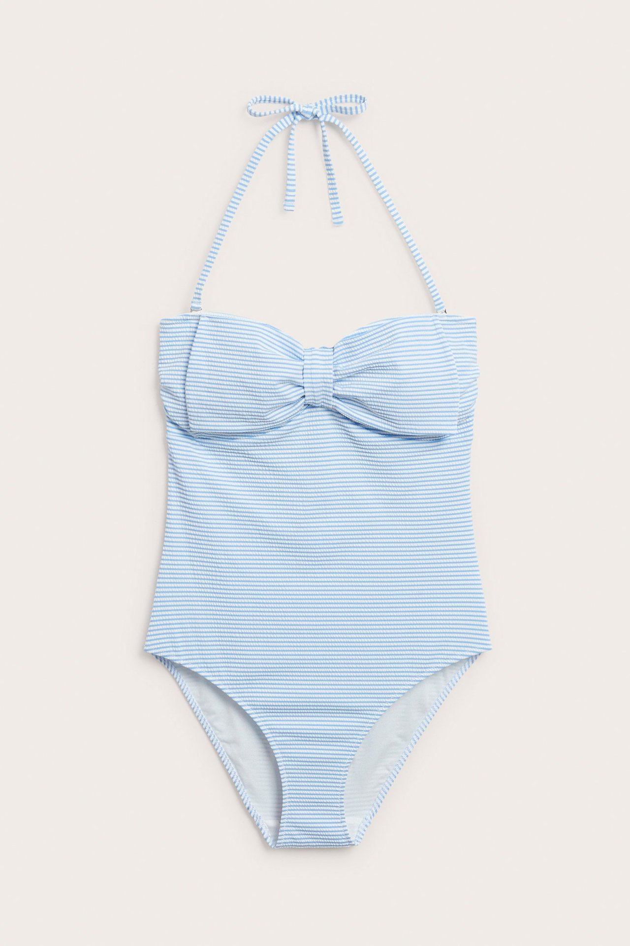 Frontvy av en ljusblå-vit randig baddräkt med rosett fram och knytband i nacken.
