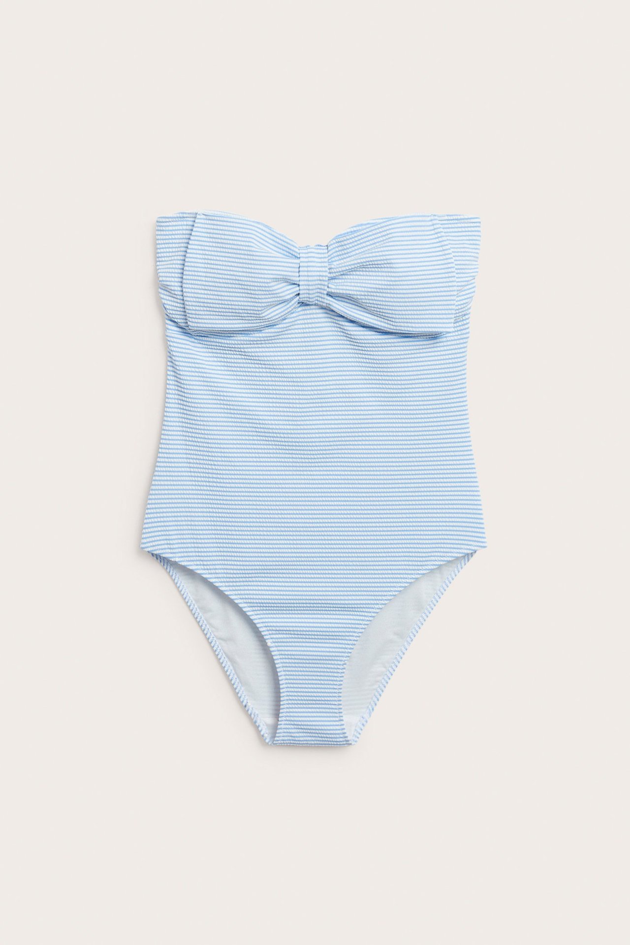 Framifrån, en blåvitrandig axelbandslös baddräkt för dam med stor rosettdetalj vid bysten.