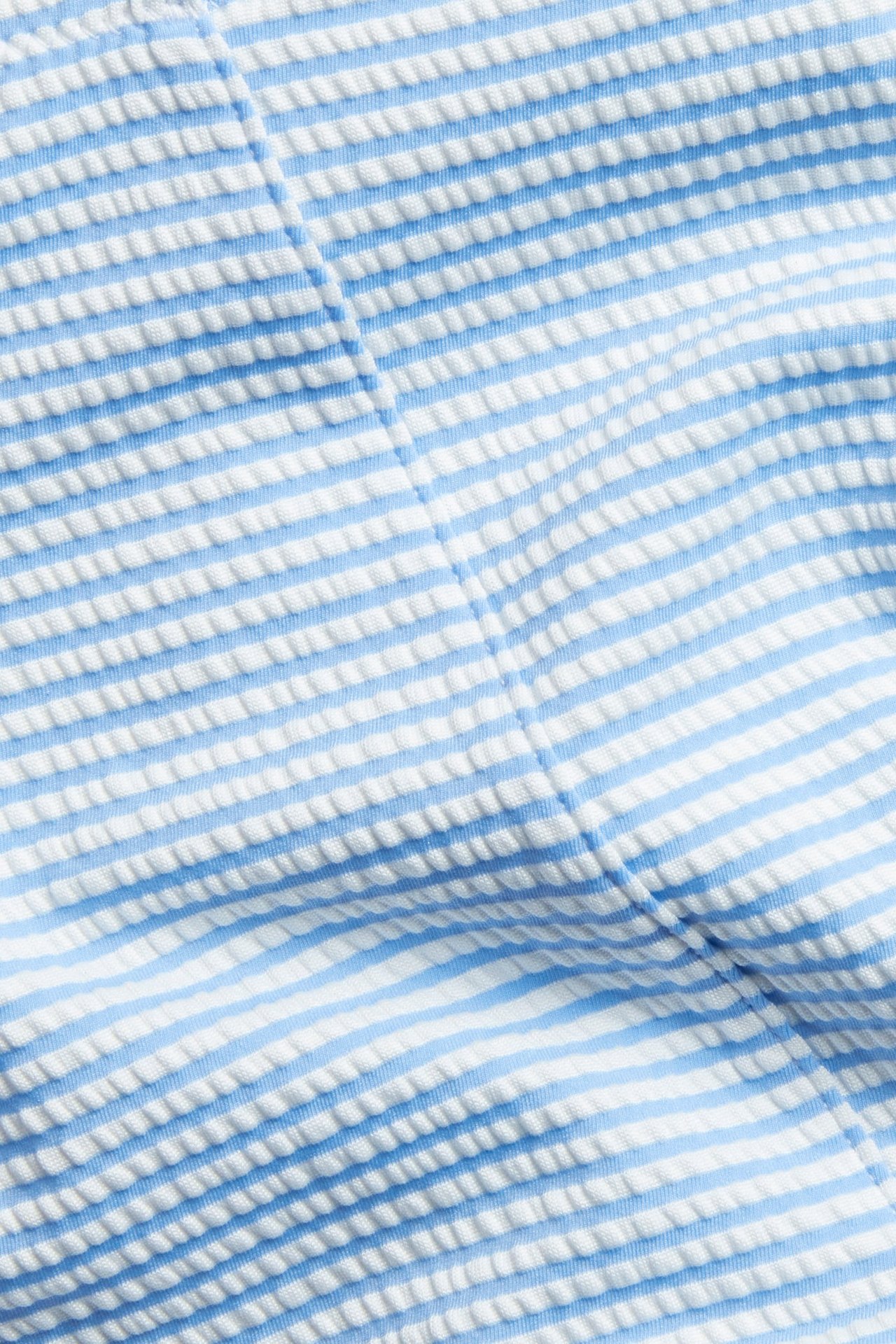 Närbild av blåvita randiga, strukturerade bikinitrosor med hög midja.