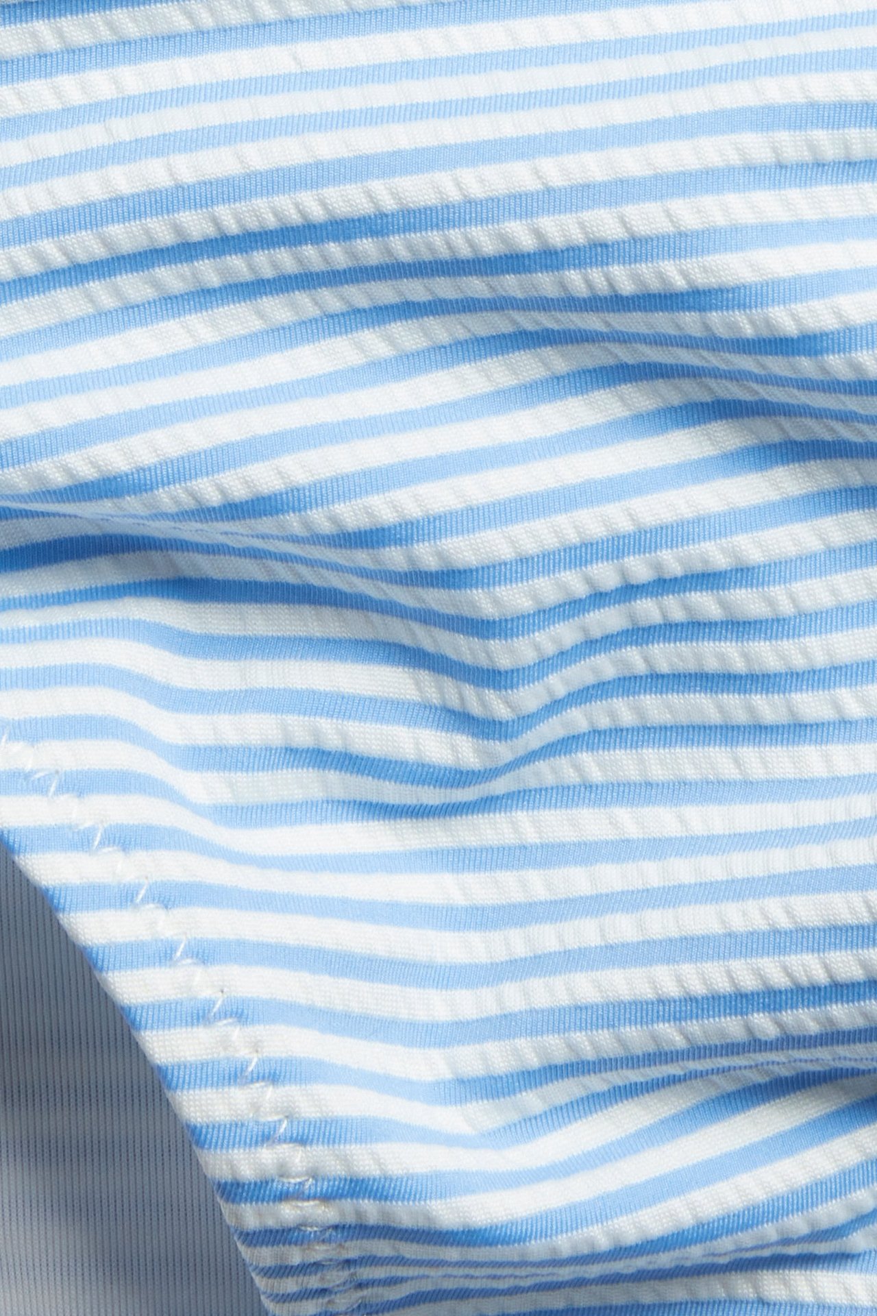 Zbliżenie na niebiesko-biały, pasiasty, teksturowany materiał od majtek bikini.