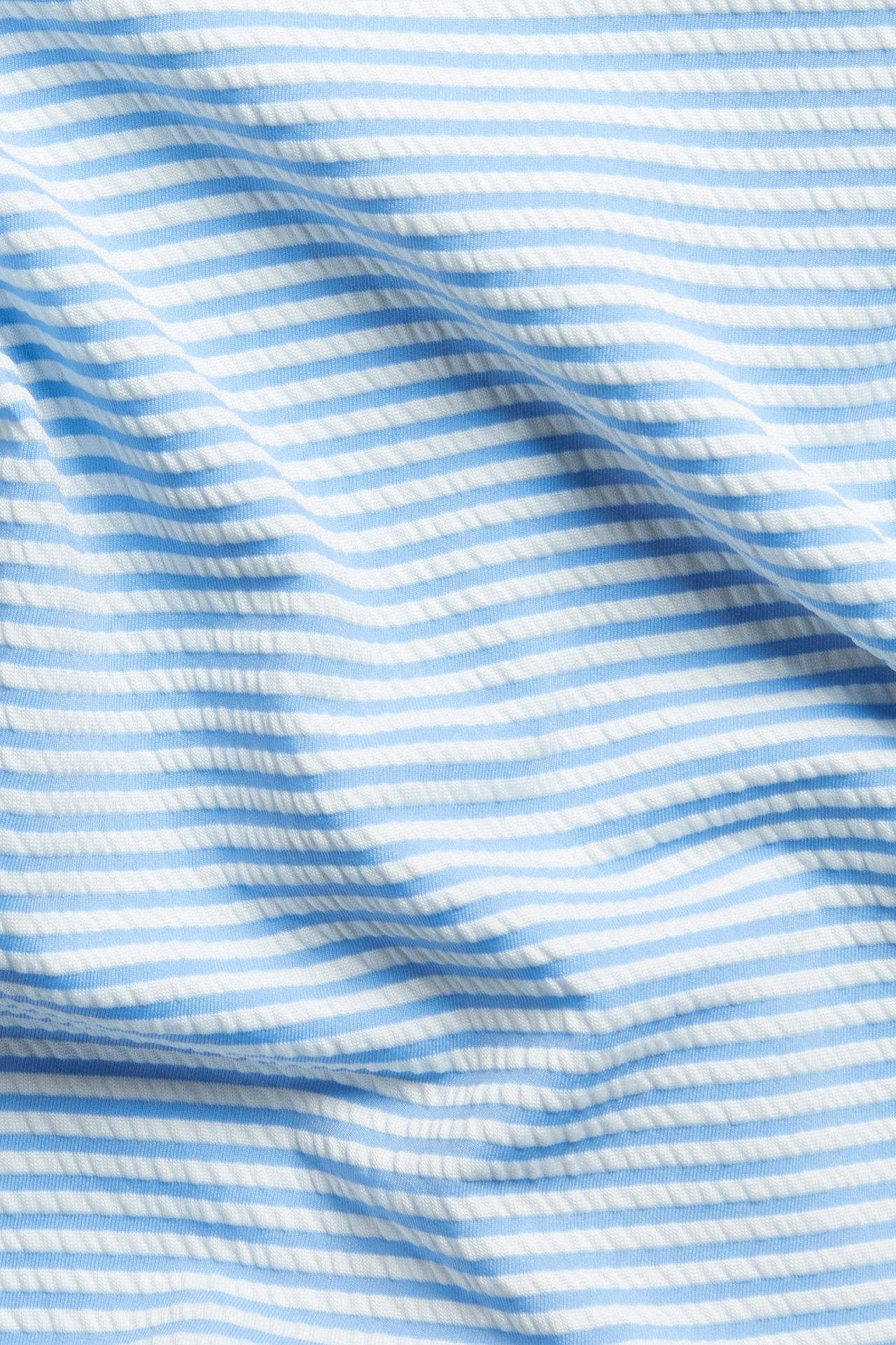 Lähikuva sinivalkoraidallisesta, uurretusta kankaasta, joka on tarkoitettu korkeavyötäröisiin bikinisortseihin.