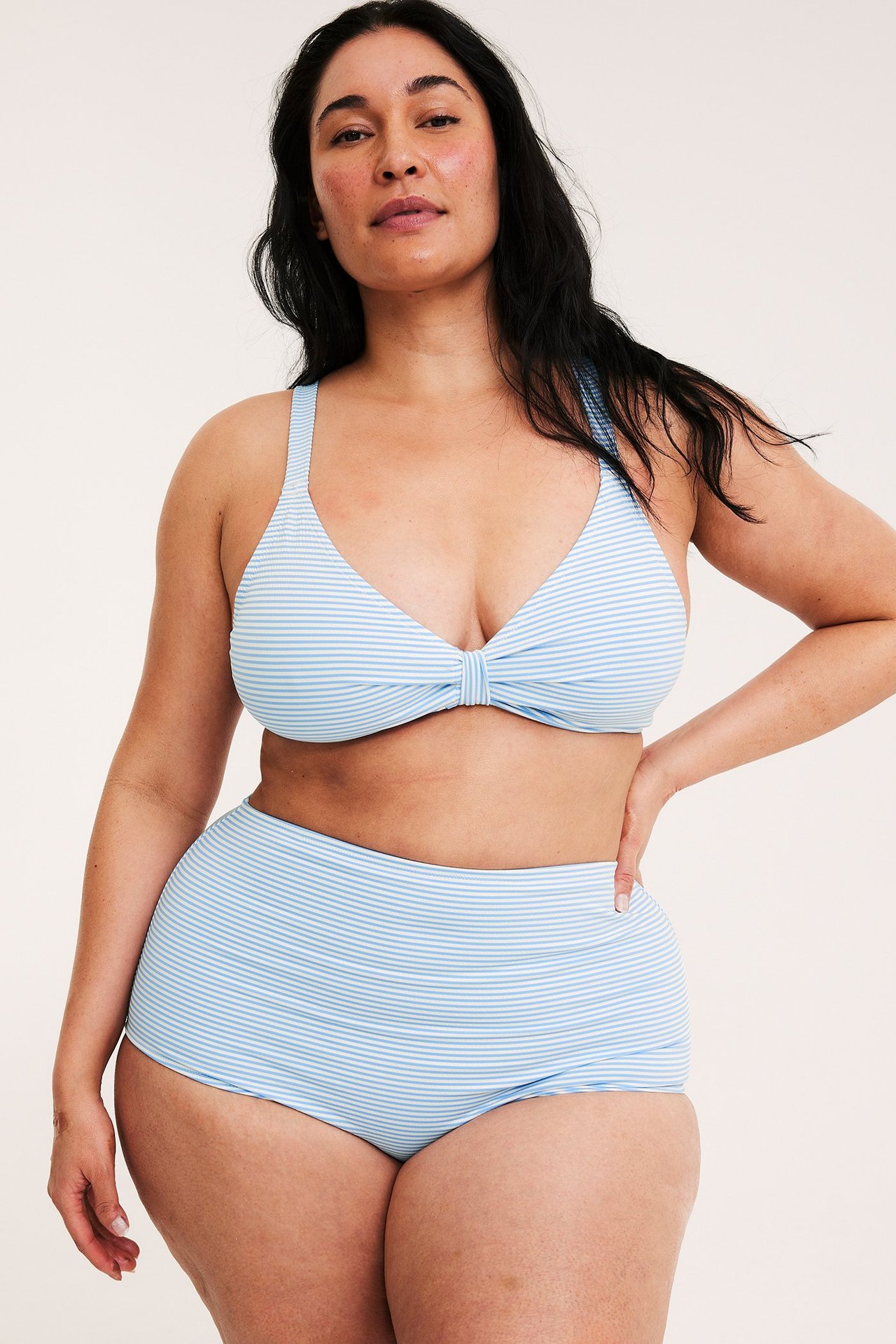 Forfra, kvinne i lysblå-hvit stripet høyt liv bikinisett.
