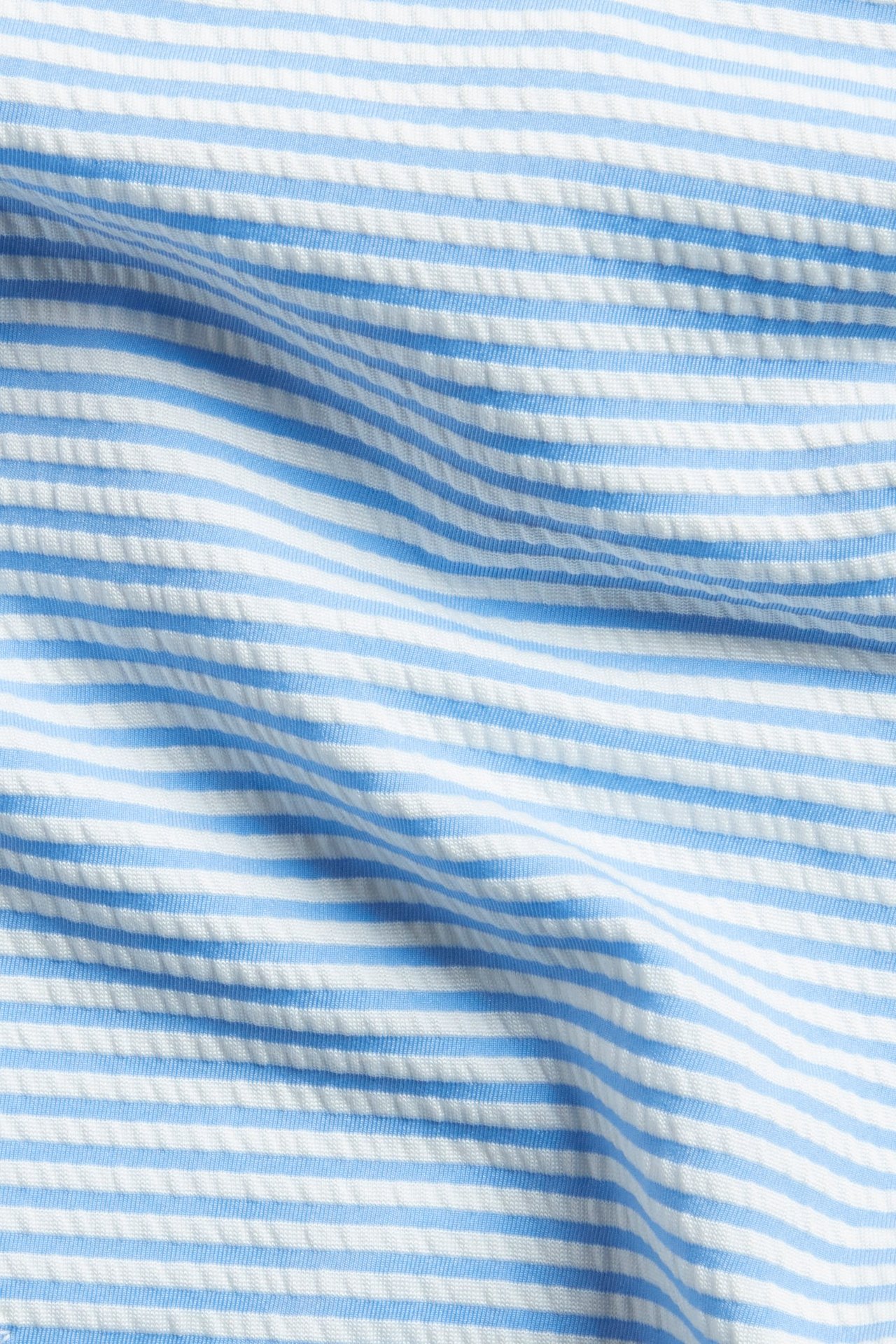 Närbild av randigt, texturerat bikinitrosmaterial i ljusblått och vitt.