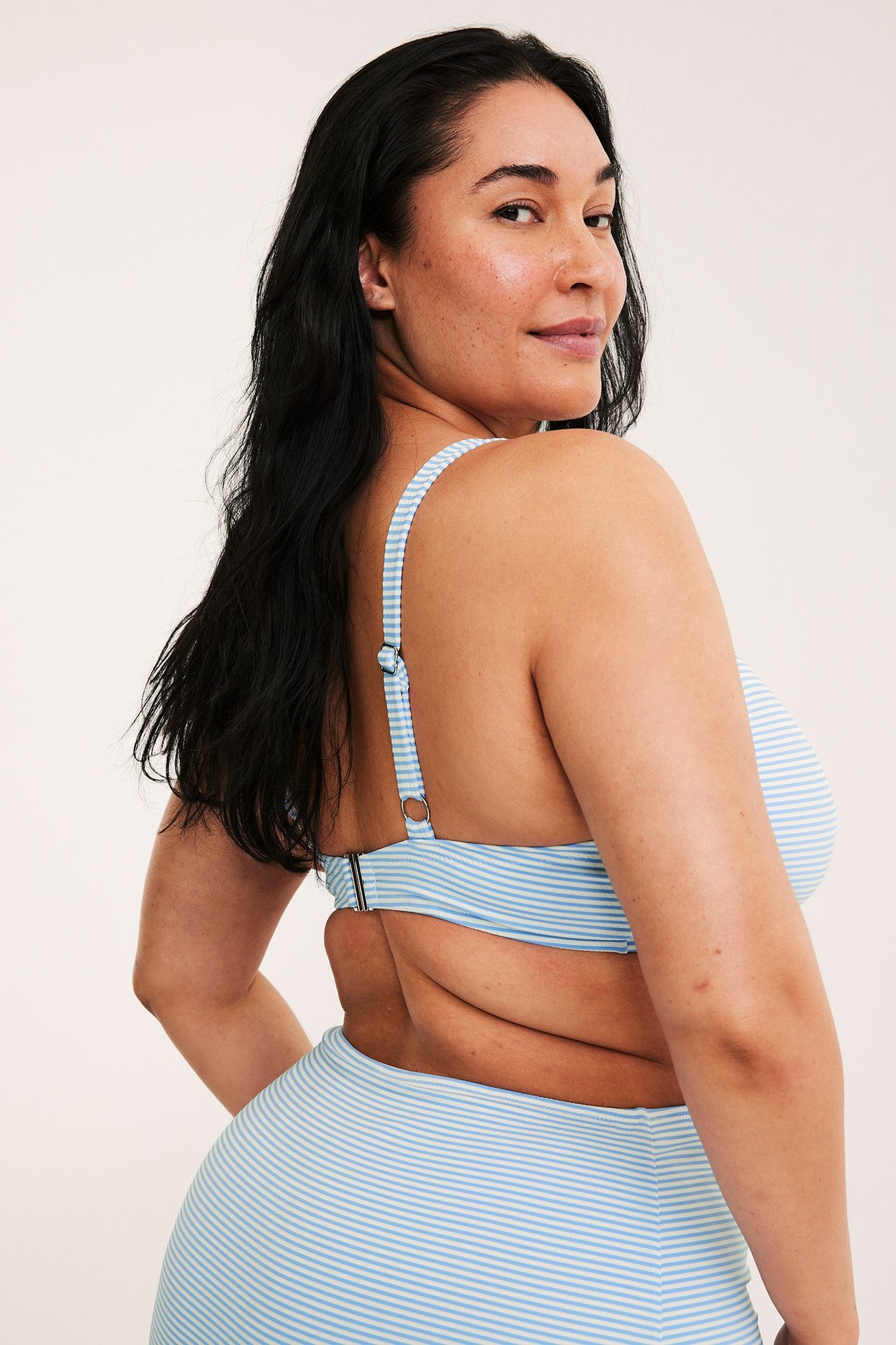 Kvinne i lys blåstripet bikinitopp med justerbare stropper, spenne bak, og matchende underdel.