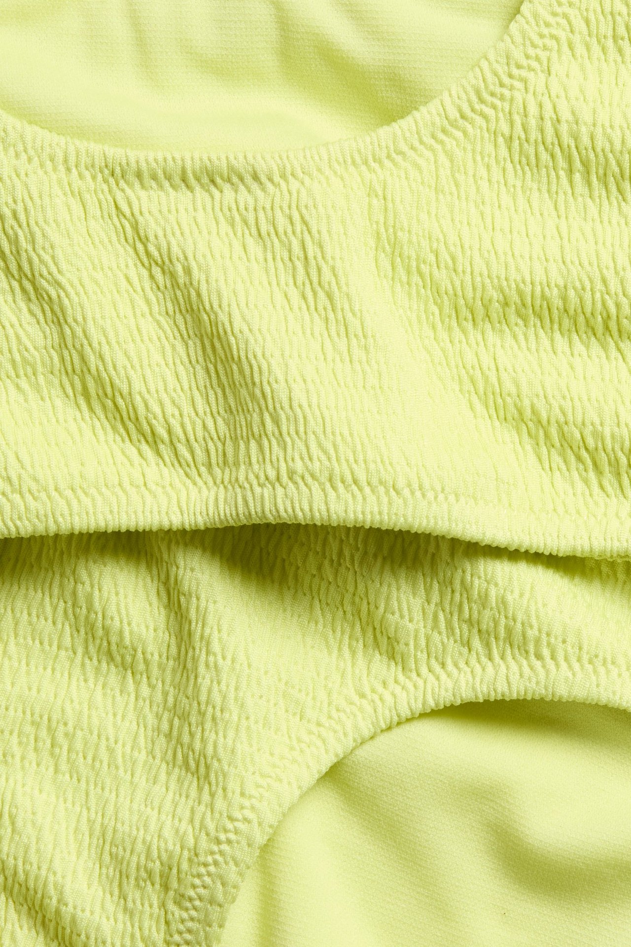 Lähikuva keltaisesta smokkirypytetystä bikinin ylä- ja alaosasta, jossa on kuvioitu kangas.