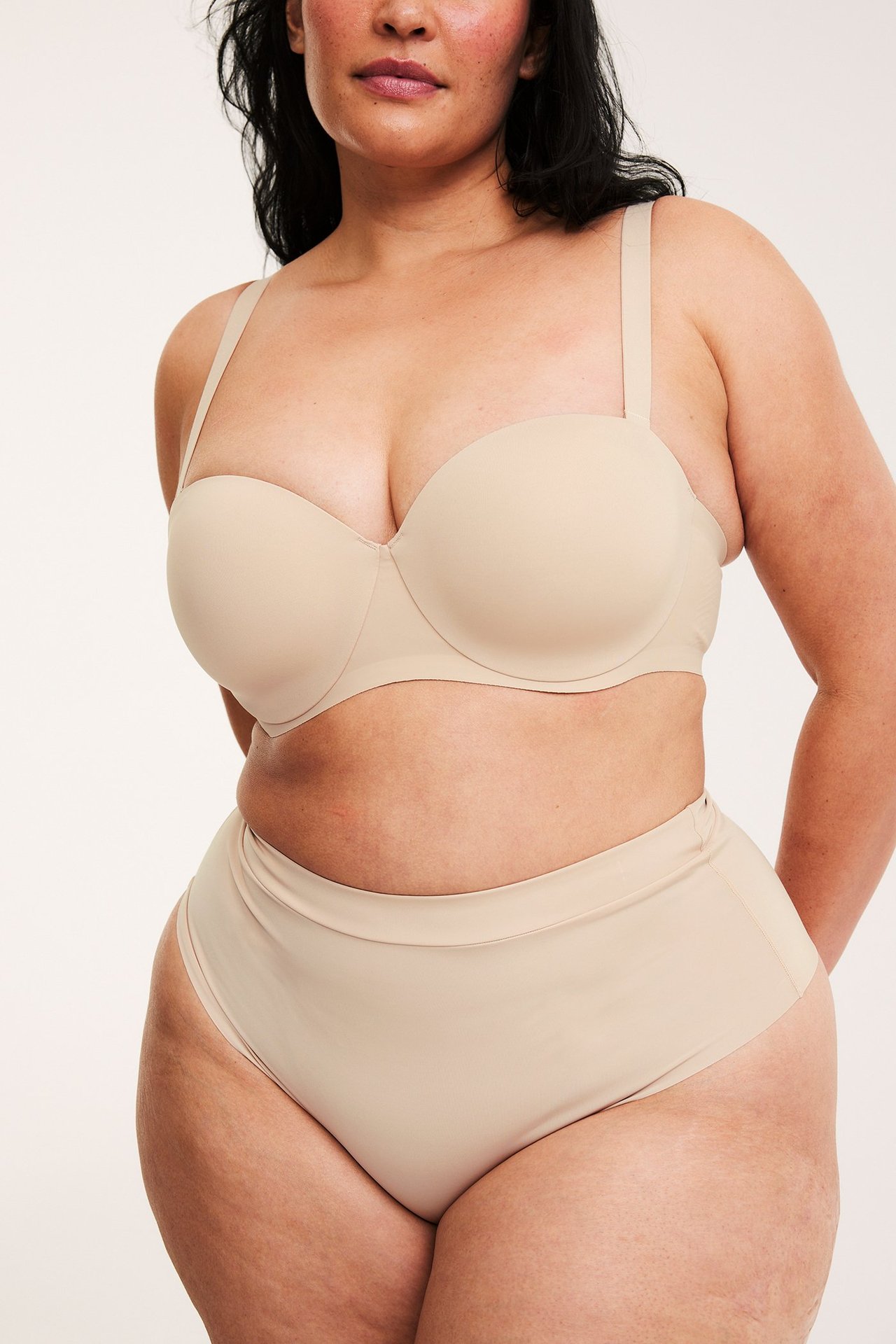 Edestä, nainen yllään vaaleanbeiget sileät mikrokuituhipsterit ja yhteensopivat olkaimettomat rintaliivit.