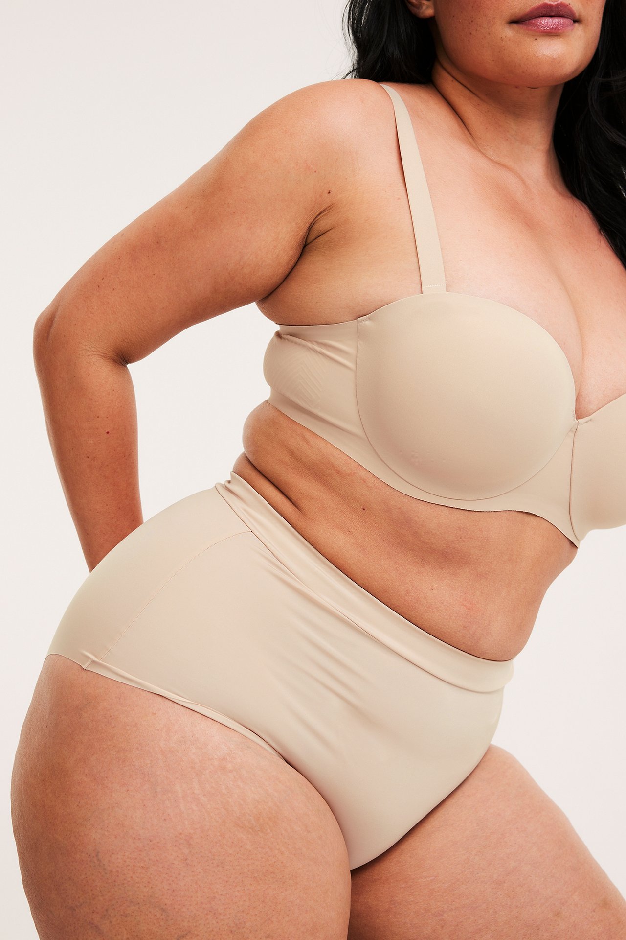 Sivukuva naisesta yllään vaaleanpunaiset saumattomat mikrokuituiset hipsteralushousut ja yhteensopivat rintaliivit.