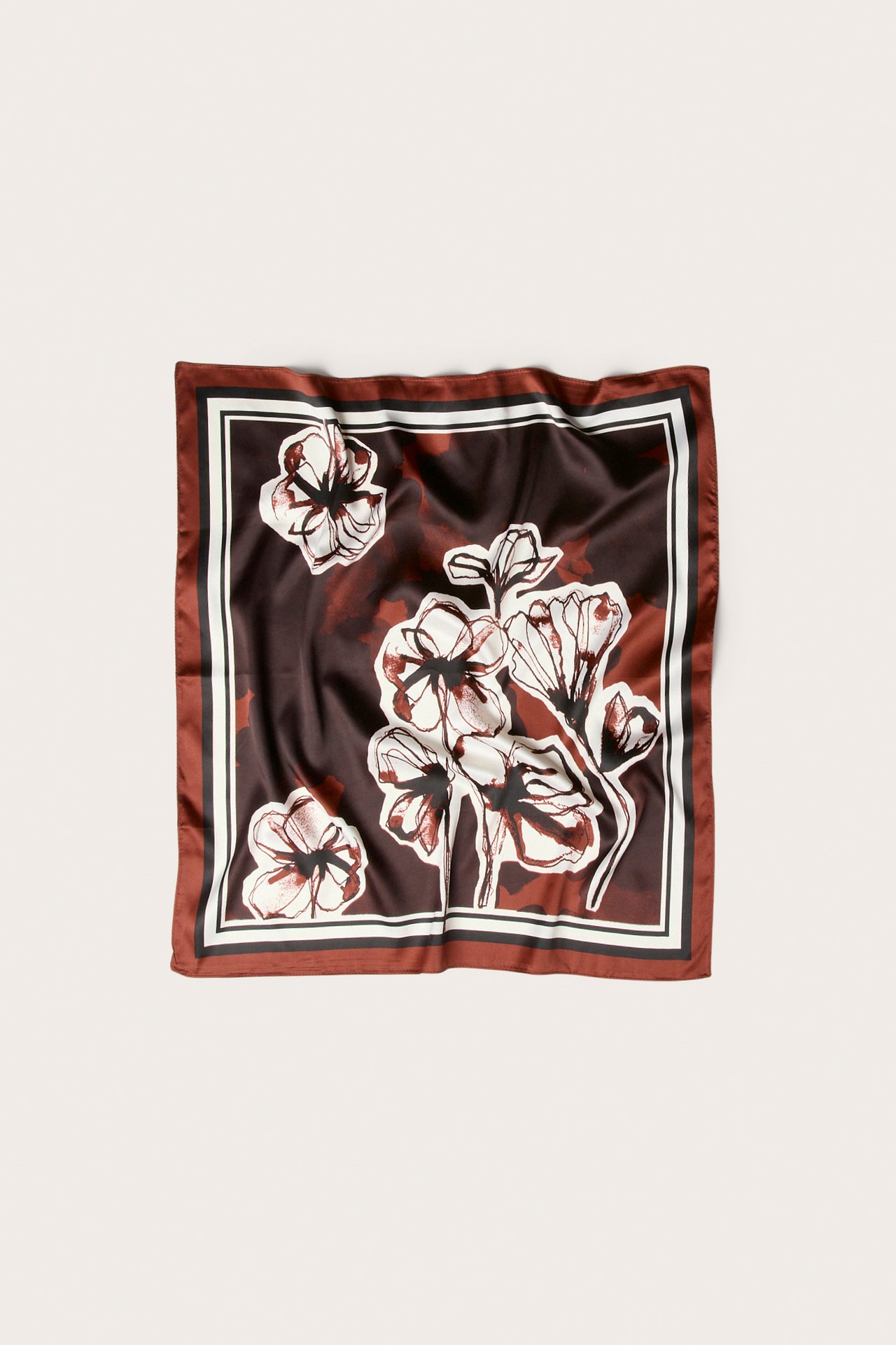 Ovanifrån: Fyrkantig vinröd satinscarf med vitt och mörkt blommigt mönster.
